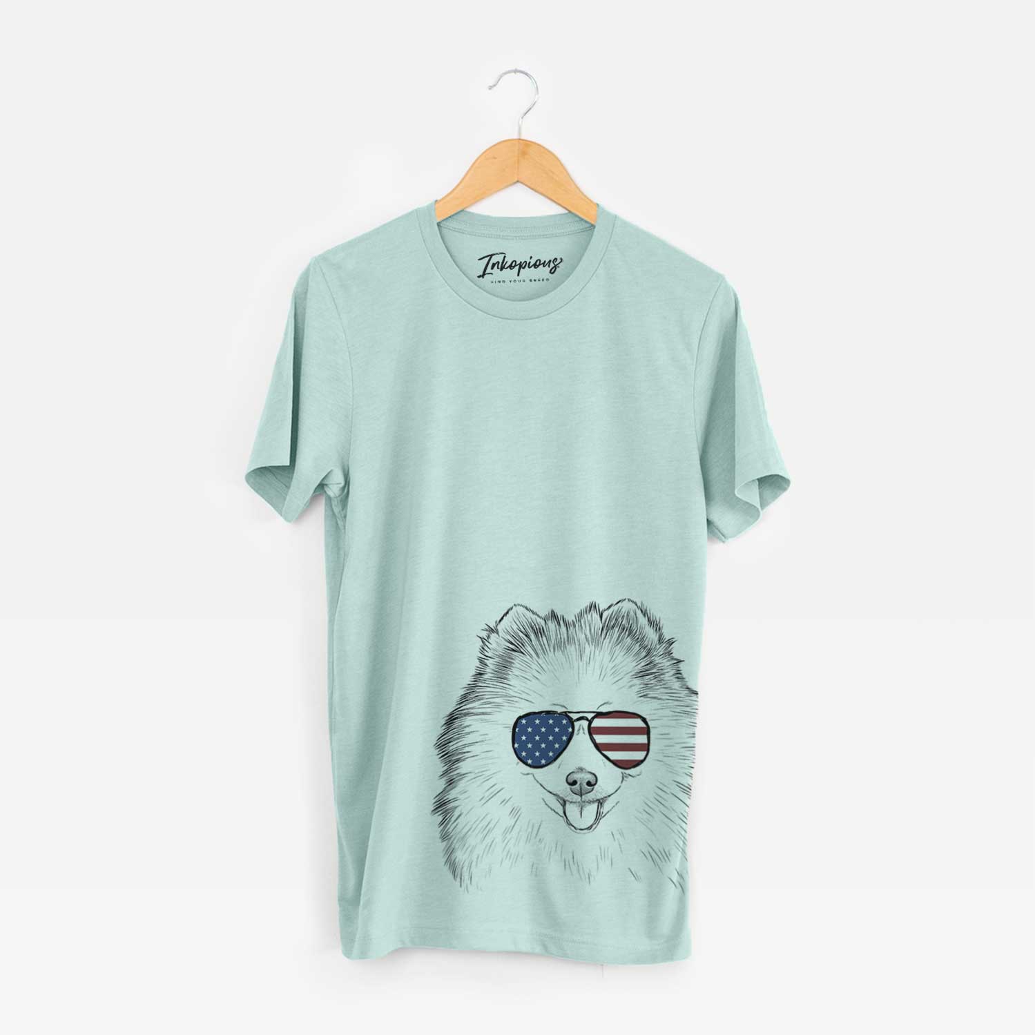 Hand-drawn sketch of Piper Jo the Pomeranian wearing American flag sunglasses on a Heather Sage Unisex crewneck
