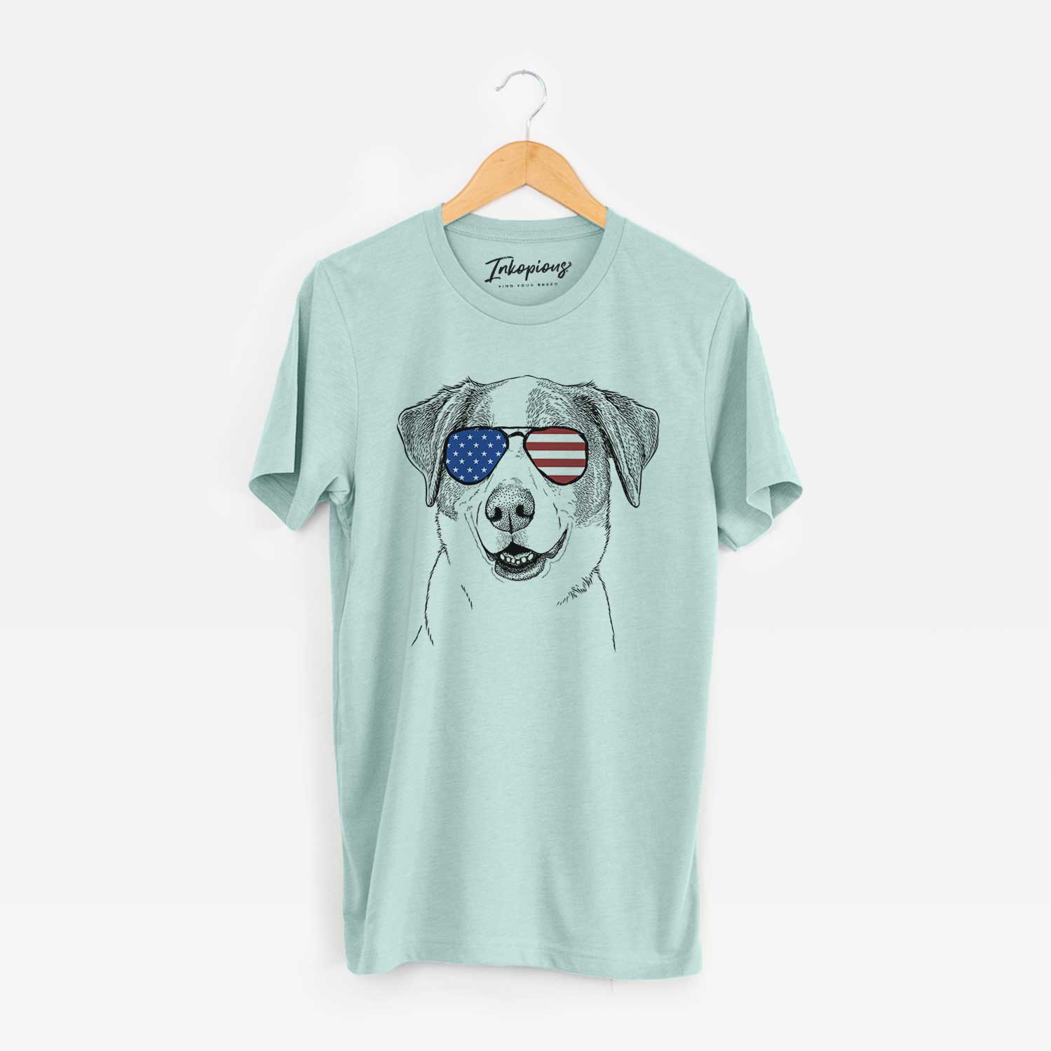 Hand-drawn sketch of Piper Pilot the Hound Mix wearing American flag sunglasses on a Heather Sage Unisex crewneck