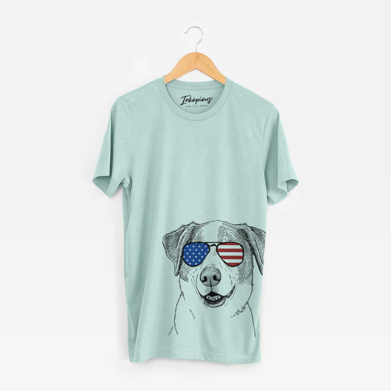 Hand-drawn sketch of Piper Pilot the Hound Mix wearing American flag sunglasses on a Heather Sage Unisex crewneck