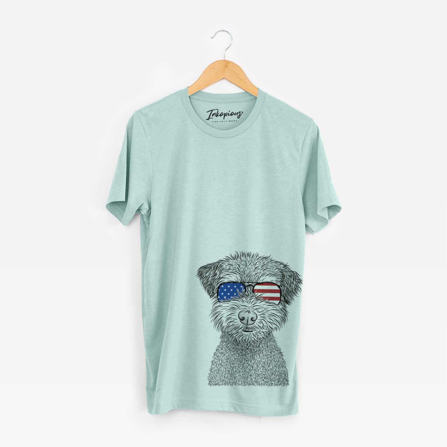 Hand-drawn sketch of Pretzel the Schnoodle wearing American flag sunglasses on a Heather Sage Unisex crewneck