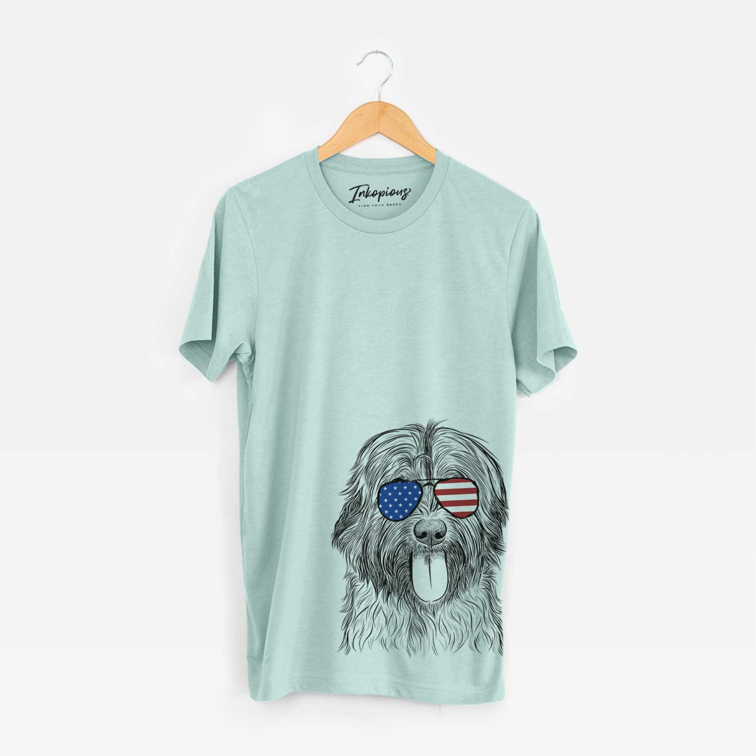 Hand-drawn sketch of Puig the Catalan Sheepdog wearing American flag sunglasses on a Heather Sage Unisex crewneck