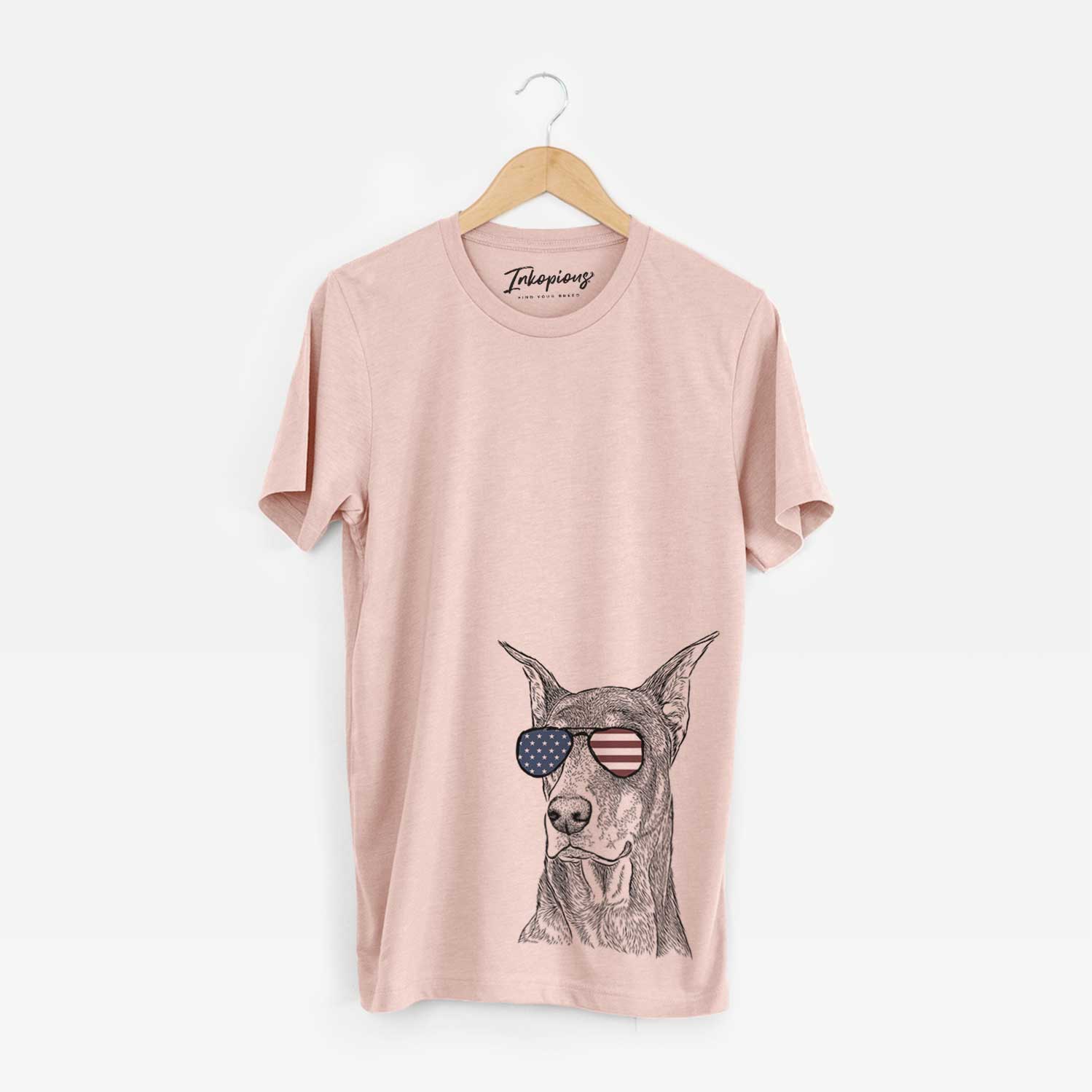 Hand-drawn sketch of RJ the Doberman Pinscher wearing American flag sunglasses on a Peach Unisex crewneck