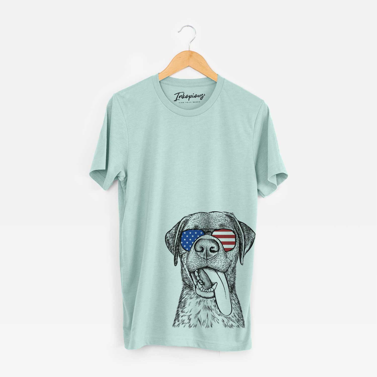 Hand-drawn sketch of Reese the Mixed Breed wearing American flag sunglasses on a Heather Sage Unisex crewneck