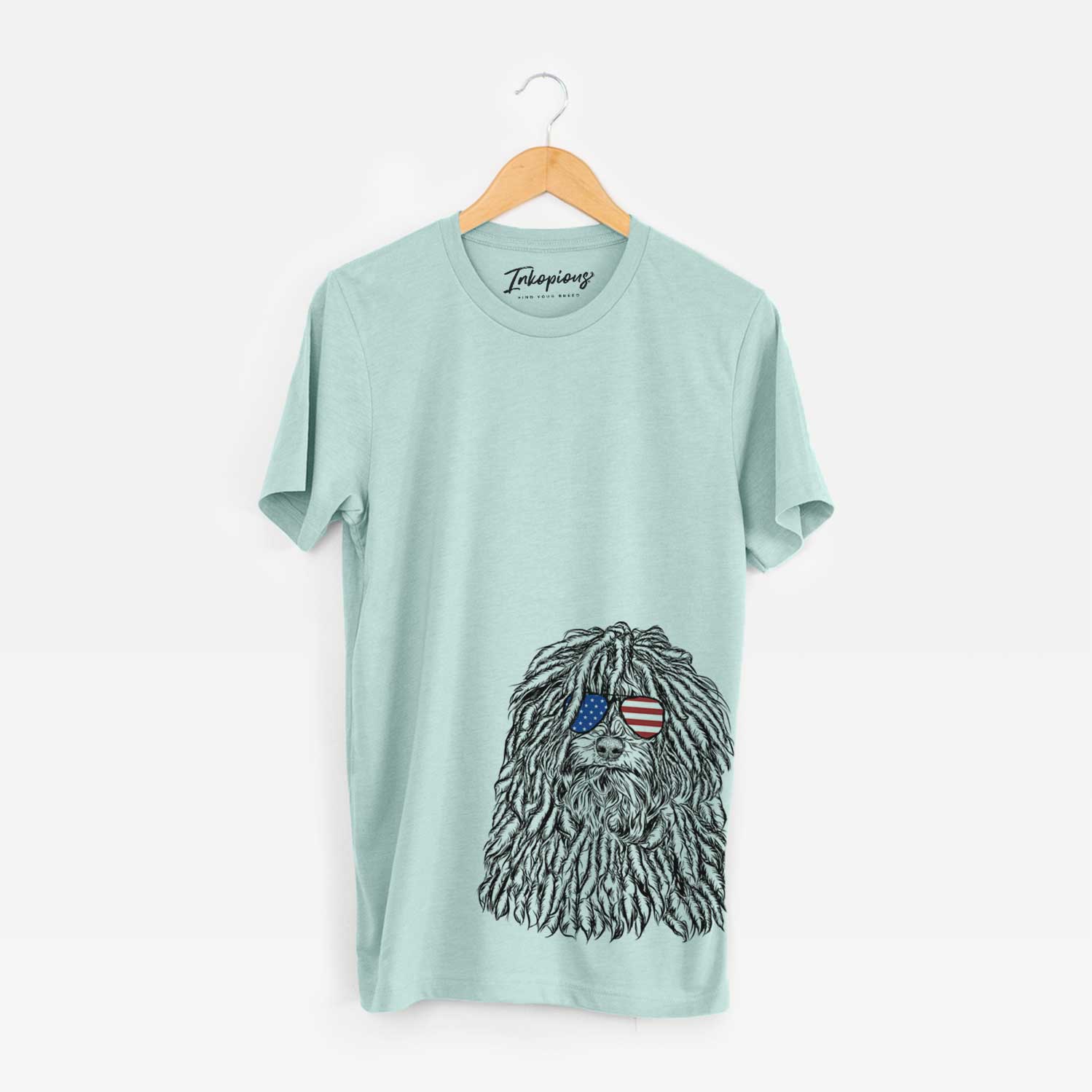 Hand-drawn sketch of Rezi the Puli wearing American flag sunglasses on a Heather Sage Unisex crewneck