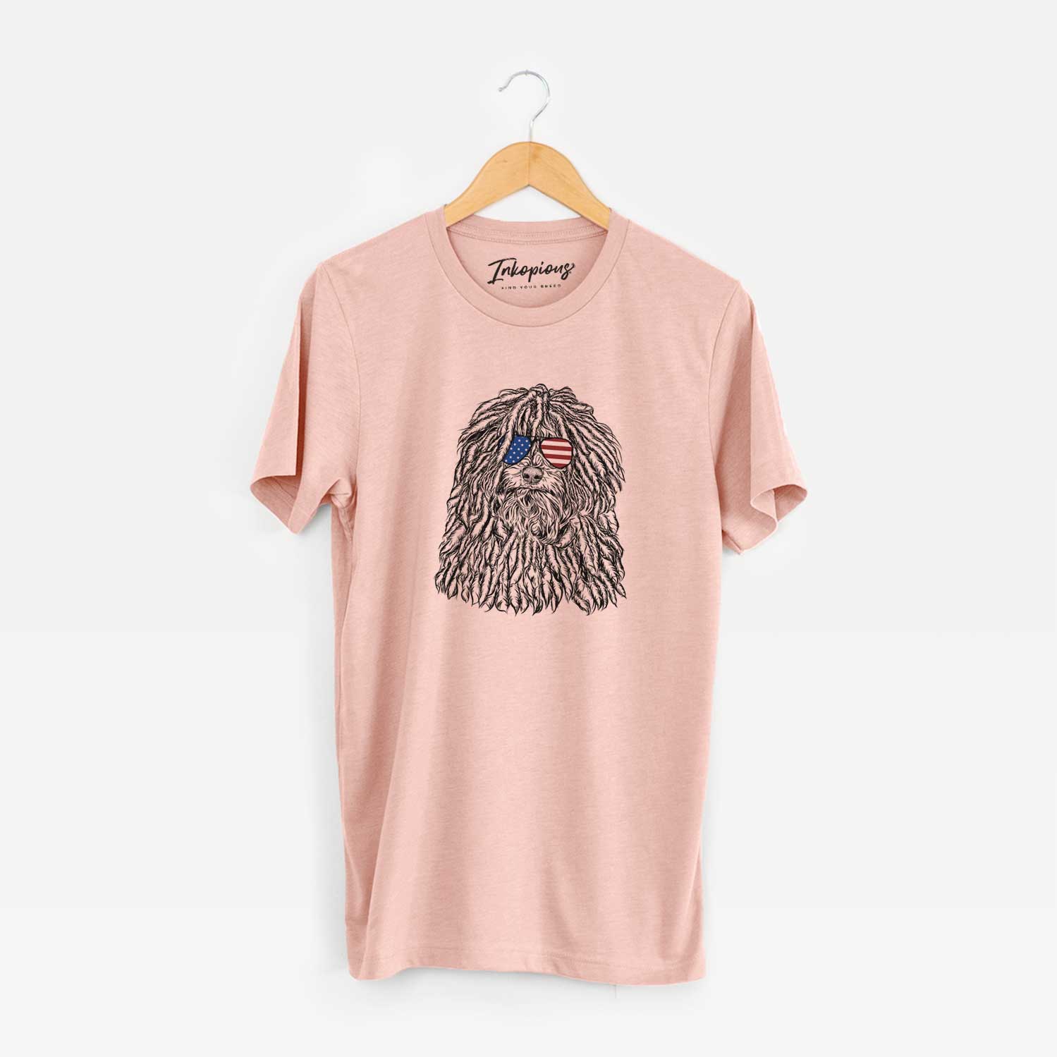 Hand-drawn sketch of Rezi the Puli wearing American flag sunglasses on a Peach Unisex crewneck