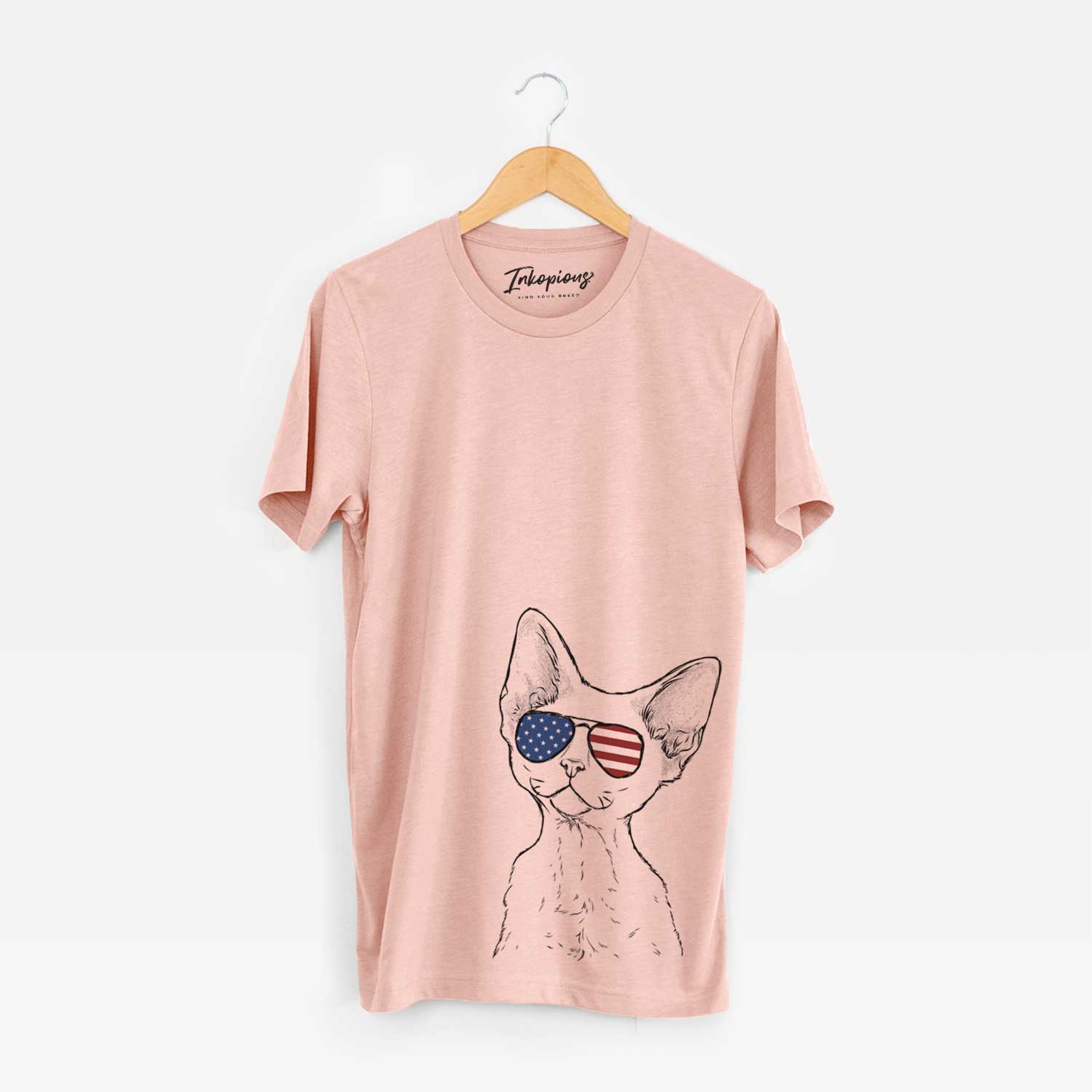 Hand-drawn sketch of Ripley the Devon Rex Cat wearing American flag sunglasses on a Peach Unisex crewneck
