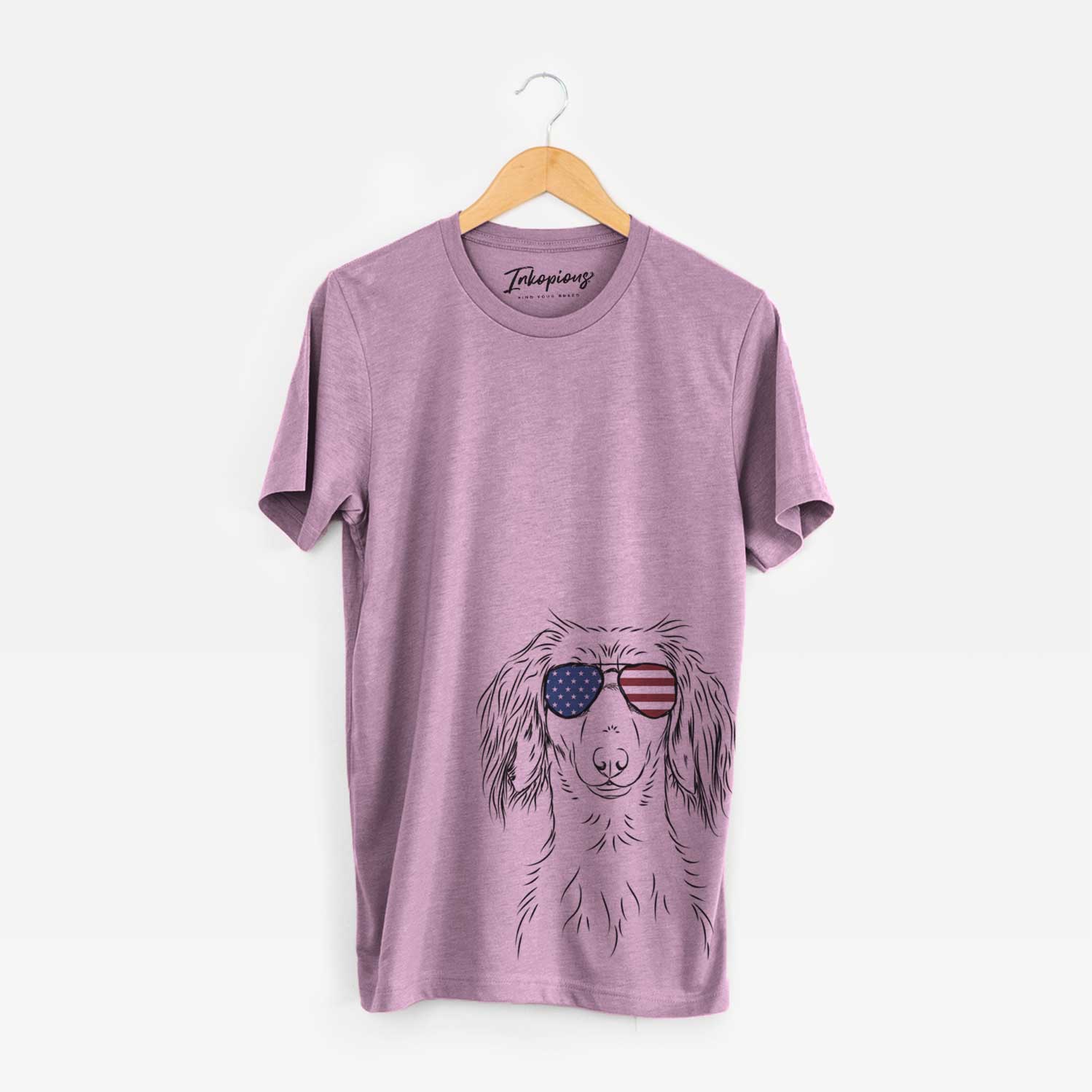 Hand-drawn sketch of Roux the Long Haired Dachshund wearing American flag sunglasses on an Orchid Unisex crewneck