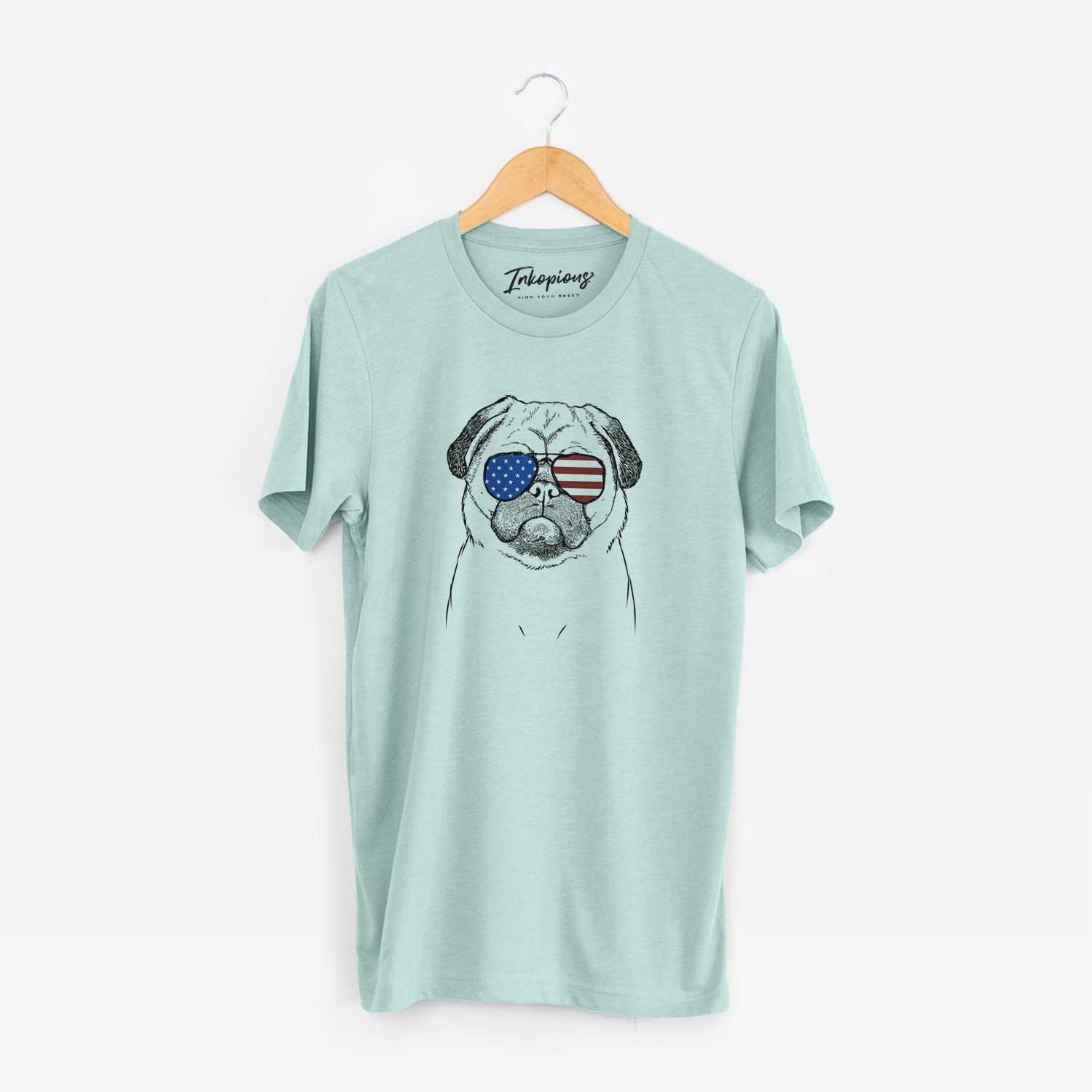 Hand-drawn sketch of Ruby the Pug wearing American flag sunglasses on a Heather Sage Unisex crewneck