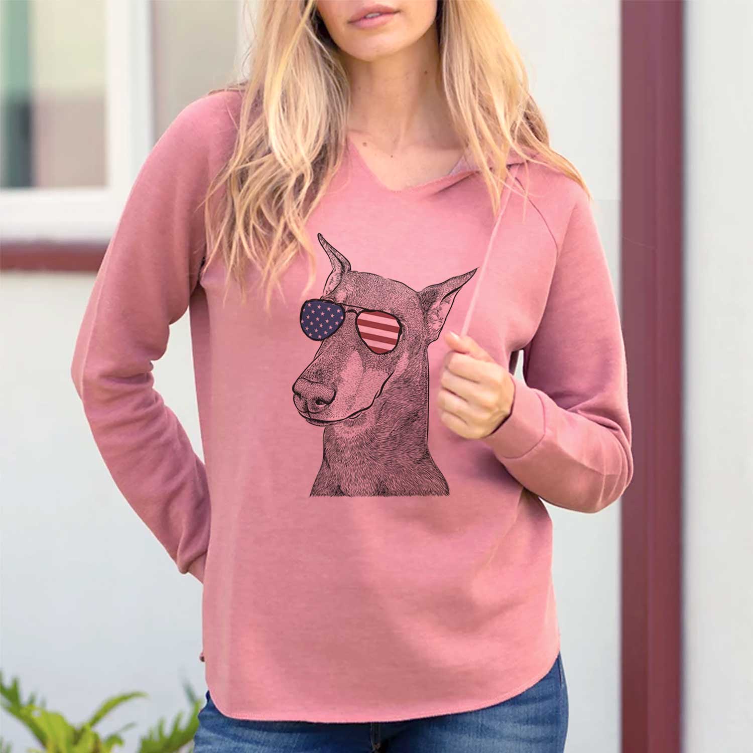 Hand-drawn sketch of Shelby the Doberman Pinscher wearing American flag sunglasses on a Dusty Rose Cali Wave Hooded Sweatshirt, lifestyle photo