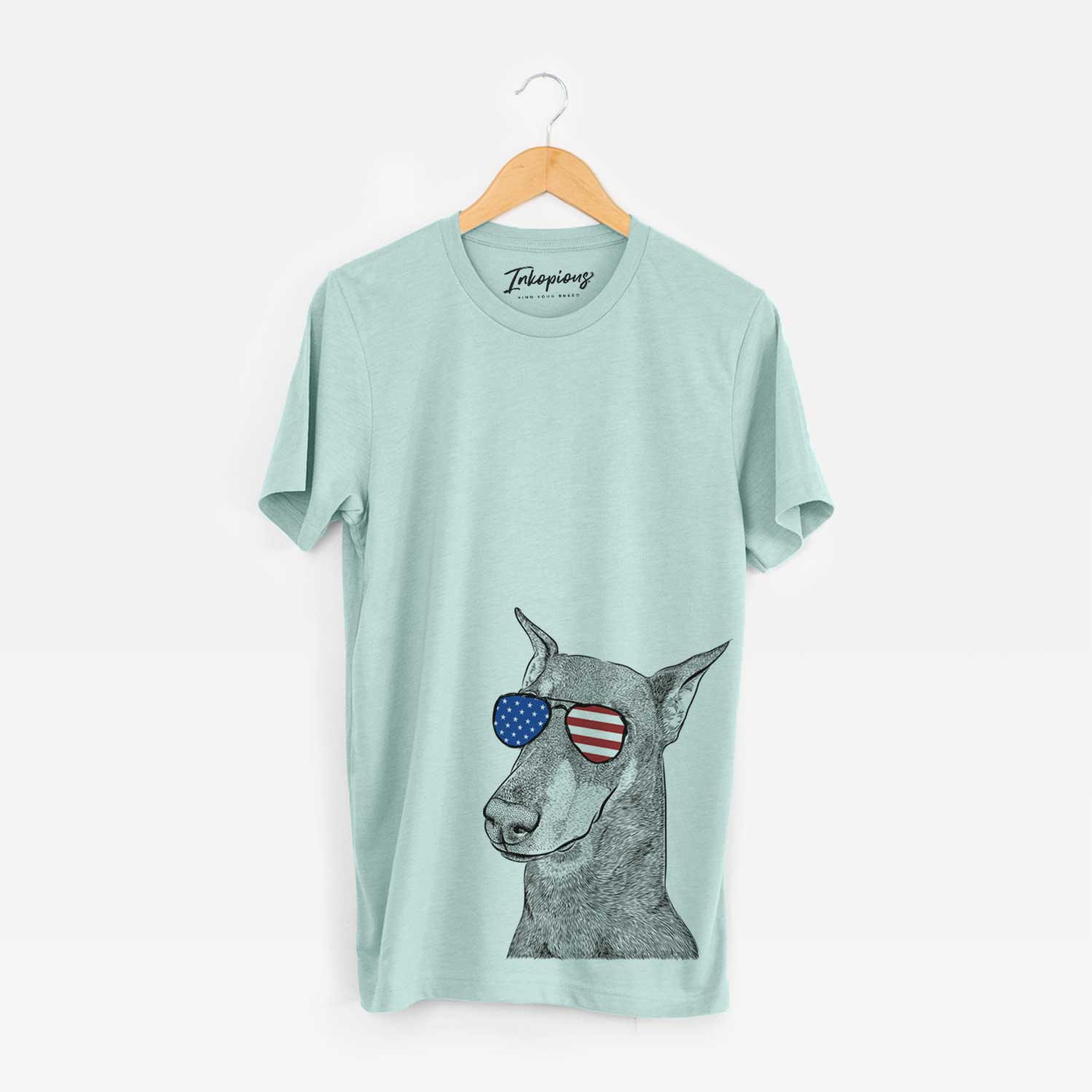 Hand-drawn sketch of Shelby the Doberman Pinscher wearing American flag sunglasses on a Heather Sage Unisex crewneck