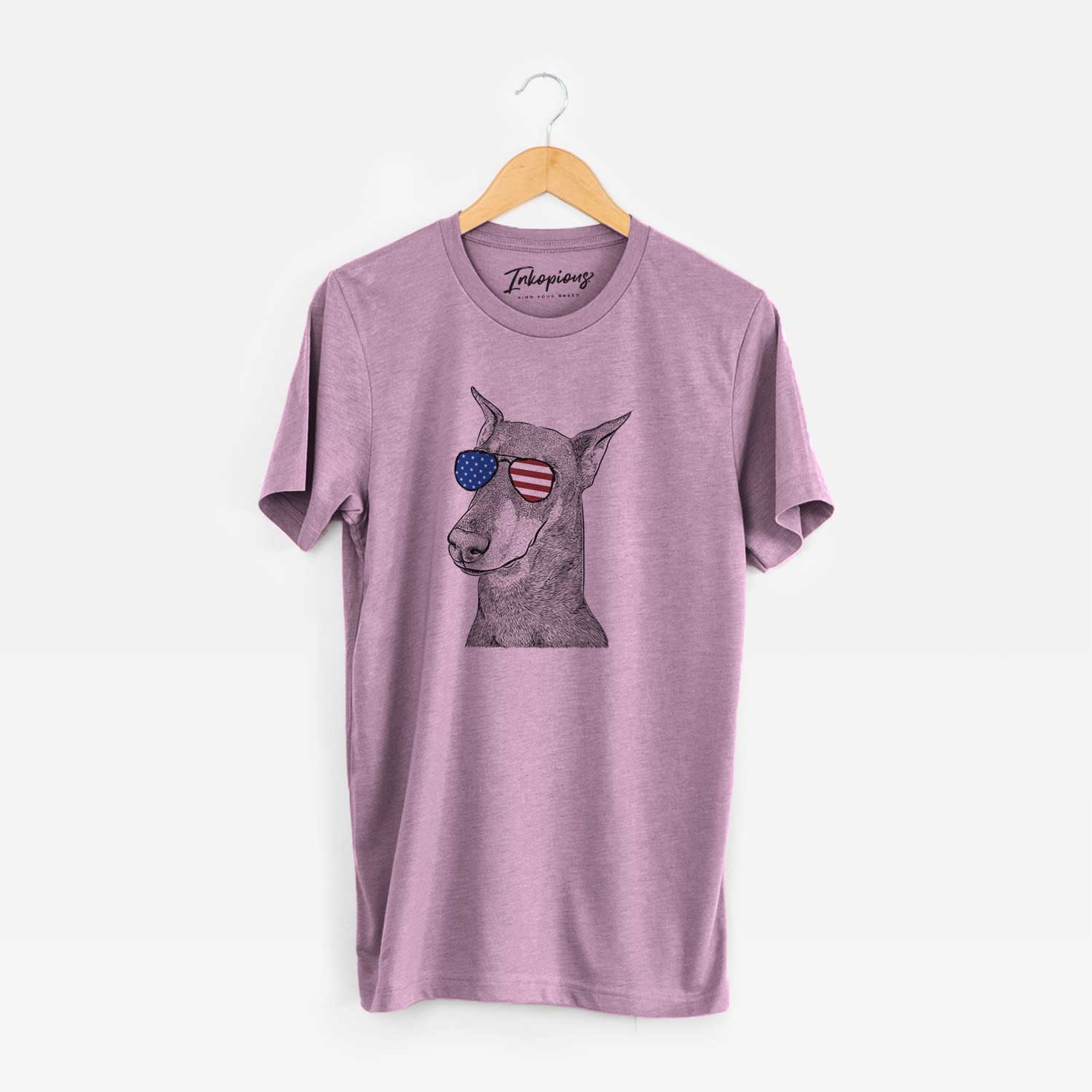 Hand-drawn sketch of Shelby the Doberman Pinscher wearing American flag sunglasses on an Orchid Unisex crewneck