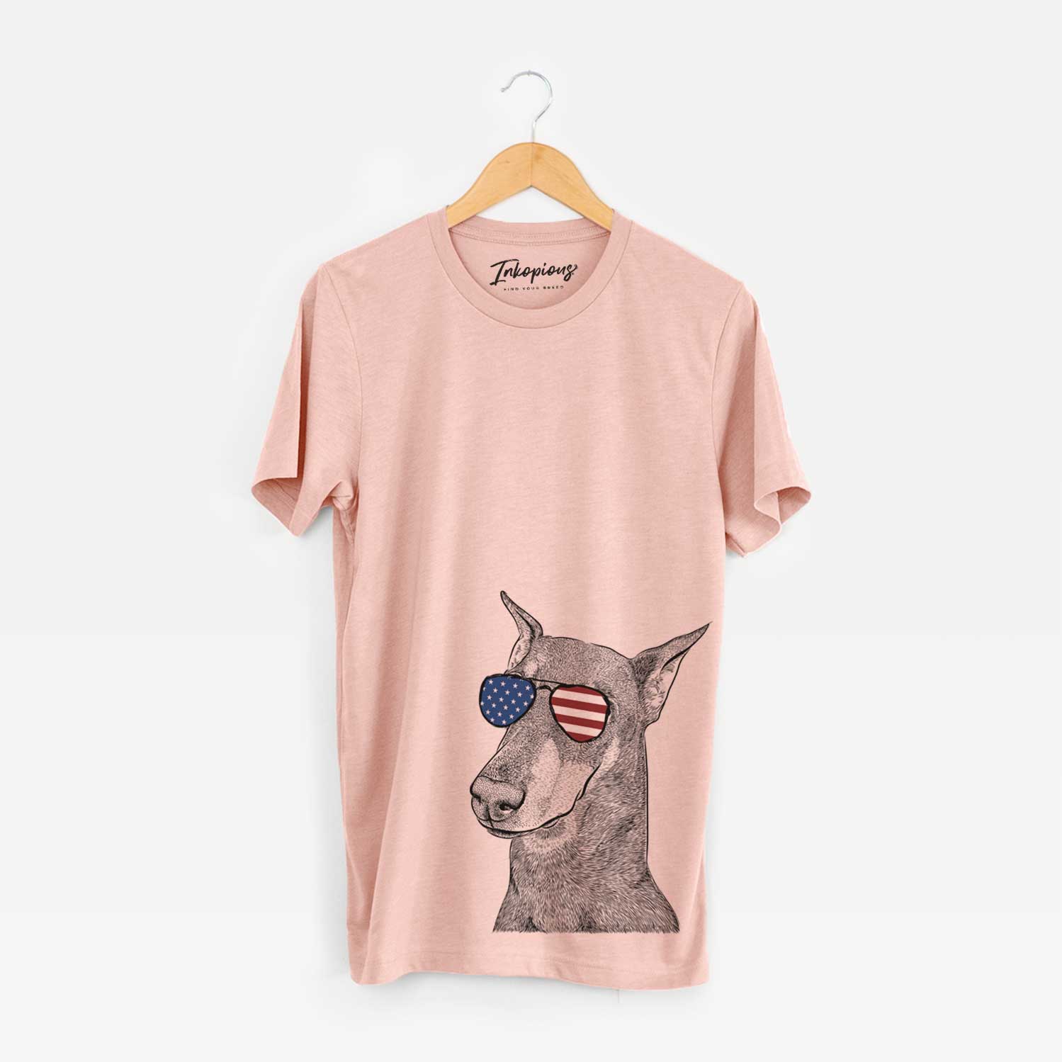 Hand-drawn sketch of Shelby the Doberman Pinscher wearing American flag sunglasses on a Peach Unisex crewneck