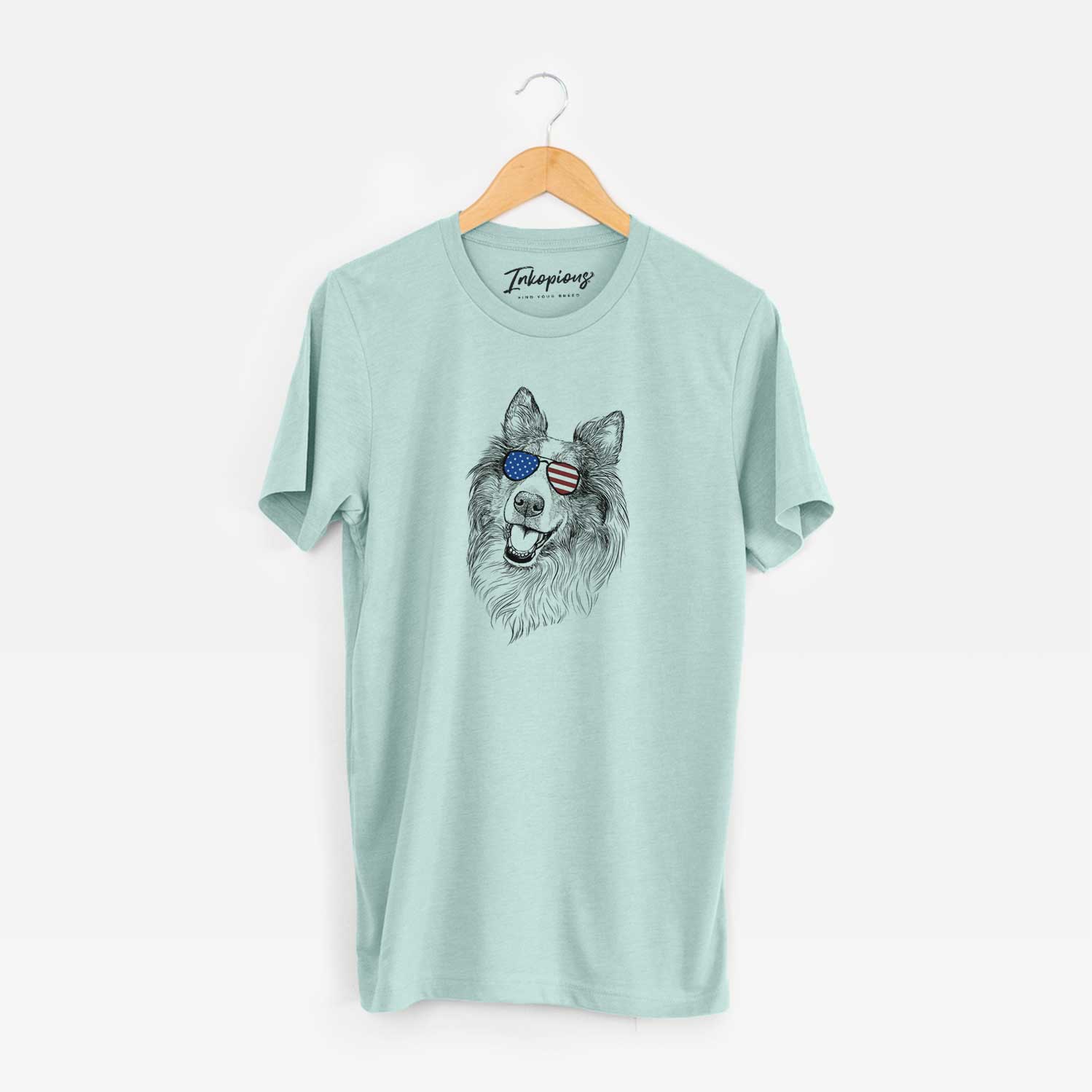 Hand-drawn sketch of Skylar the Shetland Sheepdog wearing American flag sunglasses on a Heather Sage Unisex crewneck