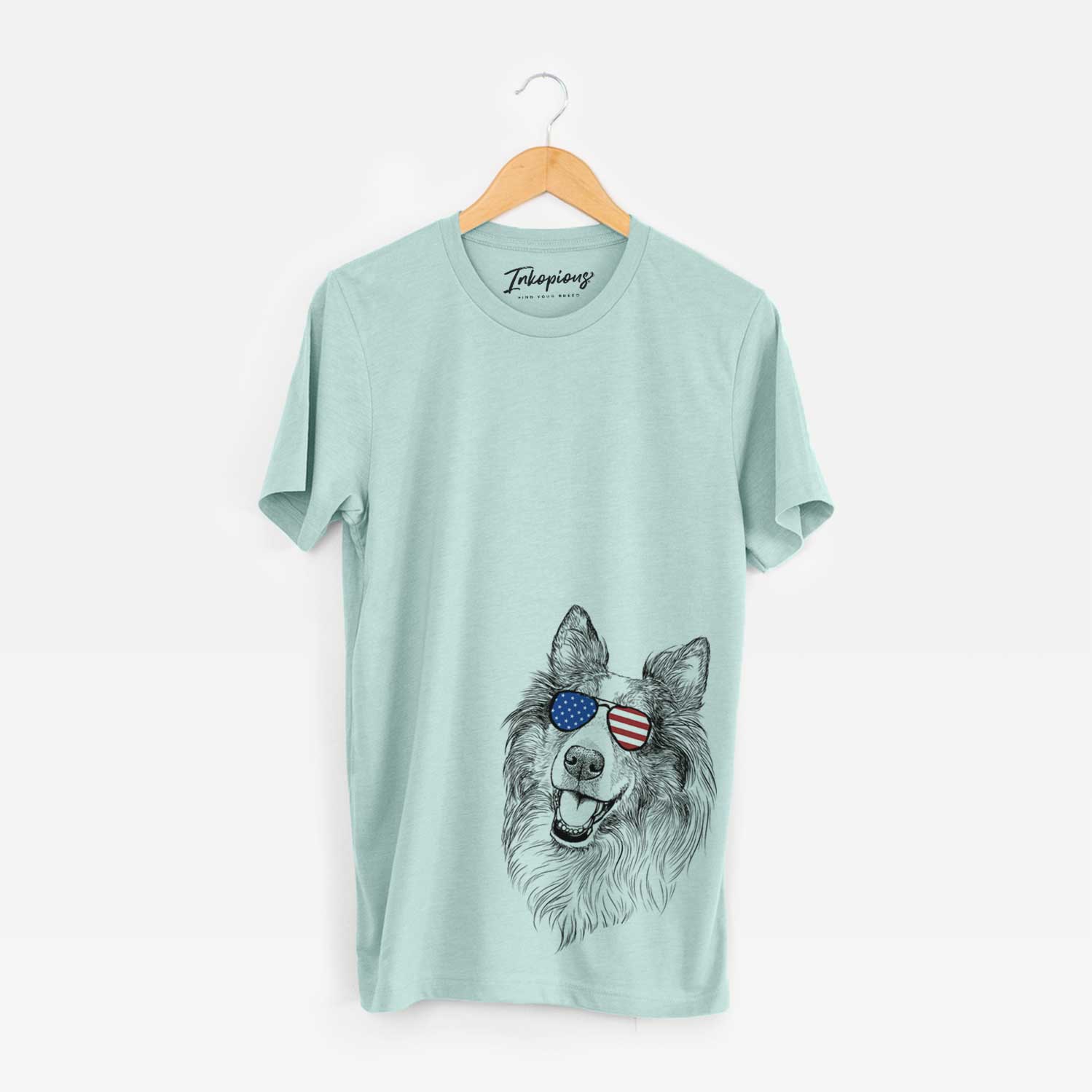 Hand-drawn sketch of Skylar the Shetland Sheepdog wearing American flag sunglasses on a Heather Sage Unisex crewneck