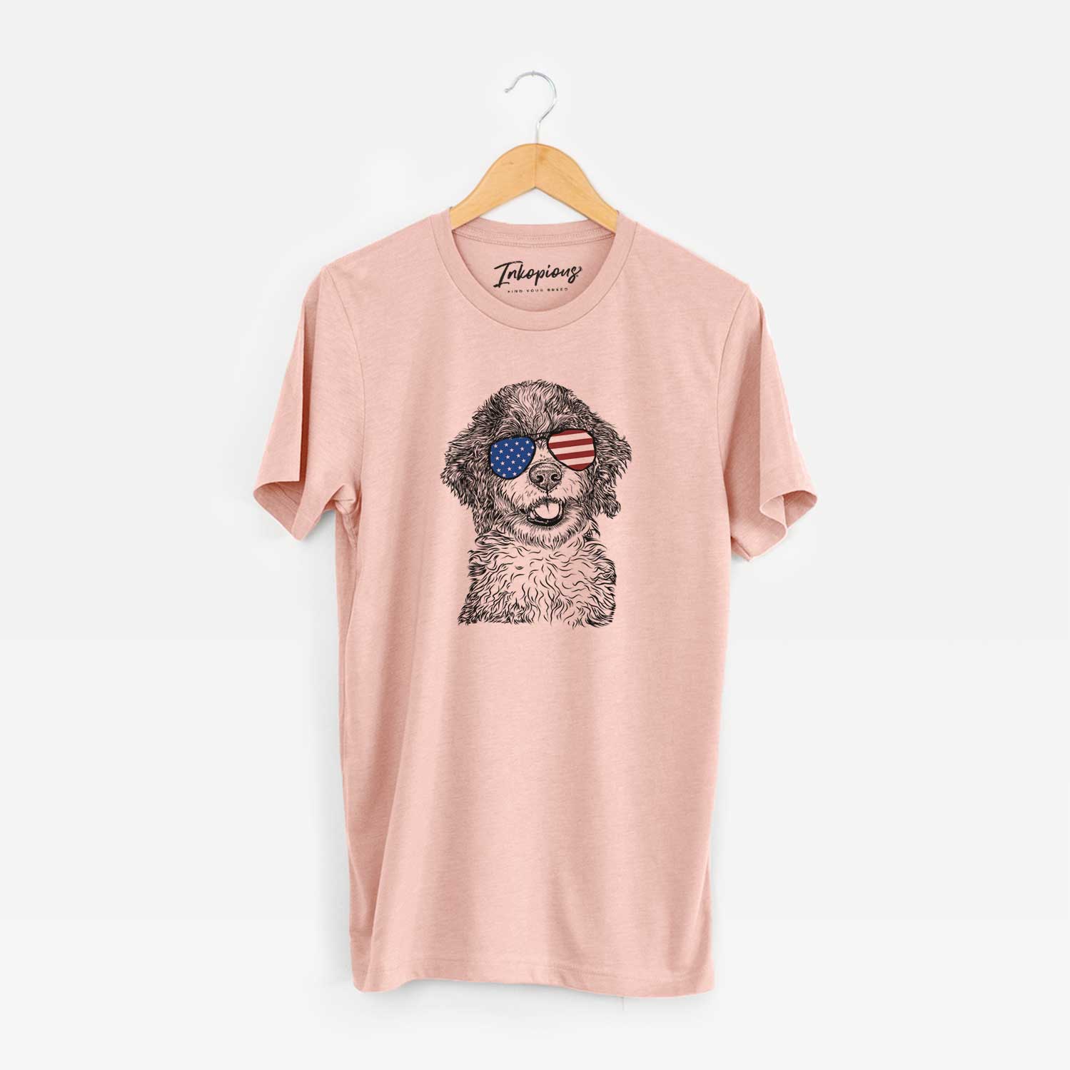 Hand-drawn sketch of Smoky the Bernedoodle Puppy wearing American flag sunglasses on a Peach Unisex crewneck