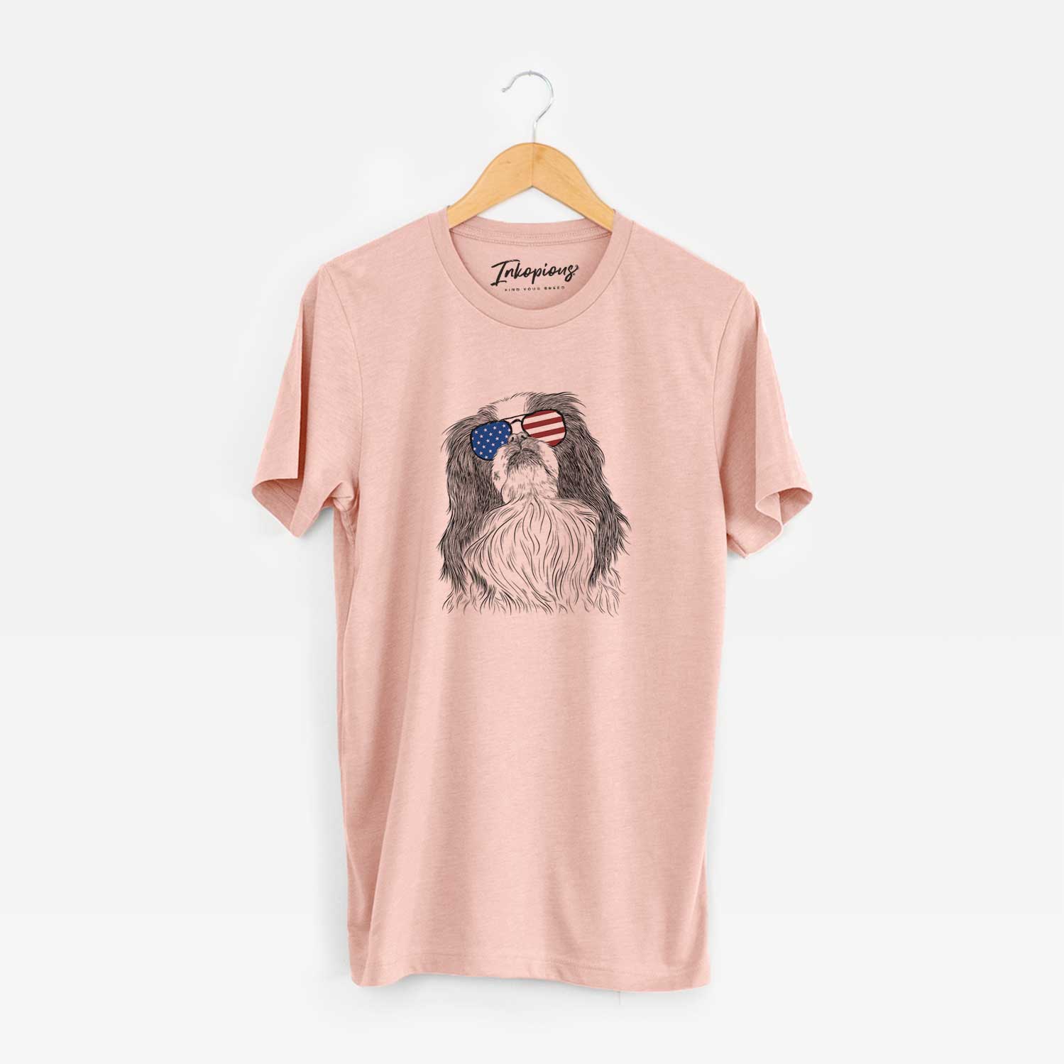 Hand-drawn sketch of Suki the Japanese Chin wearing American flag sunglasses on a Peach Unisex crewneck