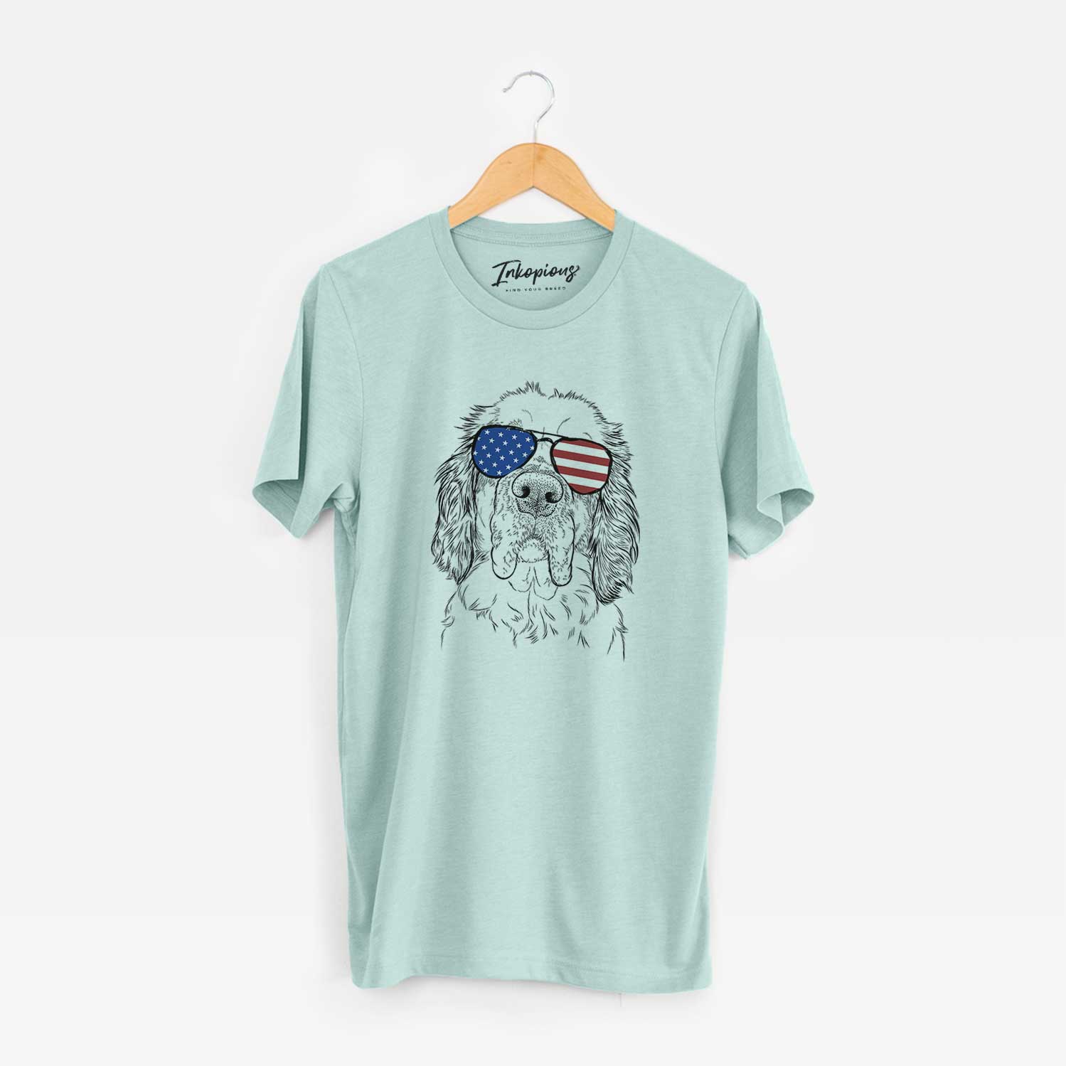 Hand-drawn sketch of Sully the Clumber Spaniel wearing American flag sunglasses on a Heather Sage Unisex crewneck