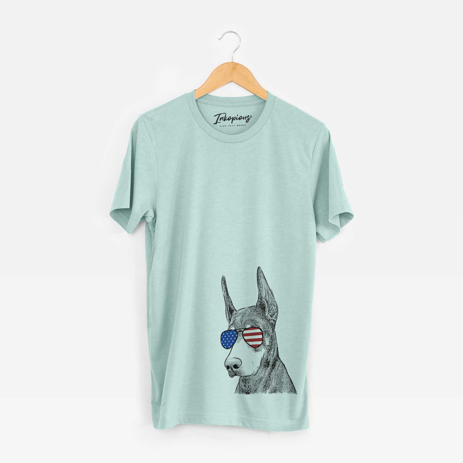 Hand-drawn sketch of Sunny the Doberman Pinscher wearing American flag sunglasses on a Heather Sage Unisex crewneck