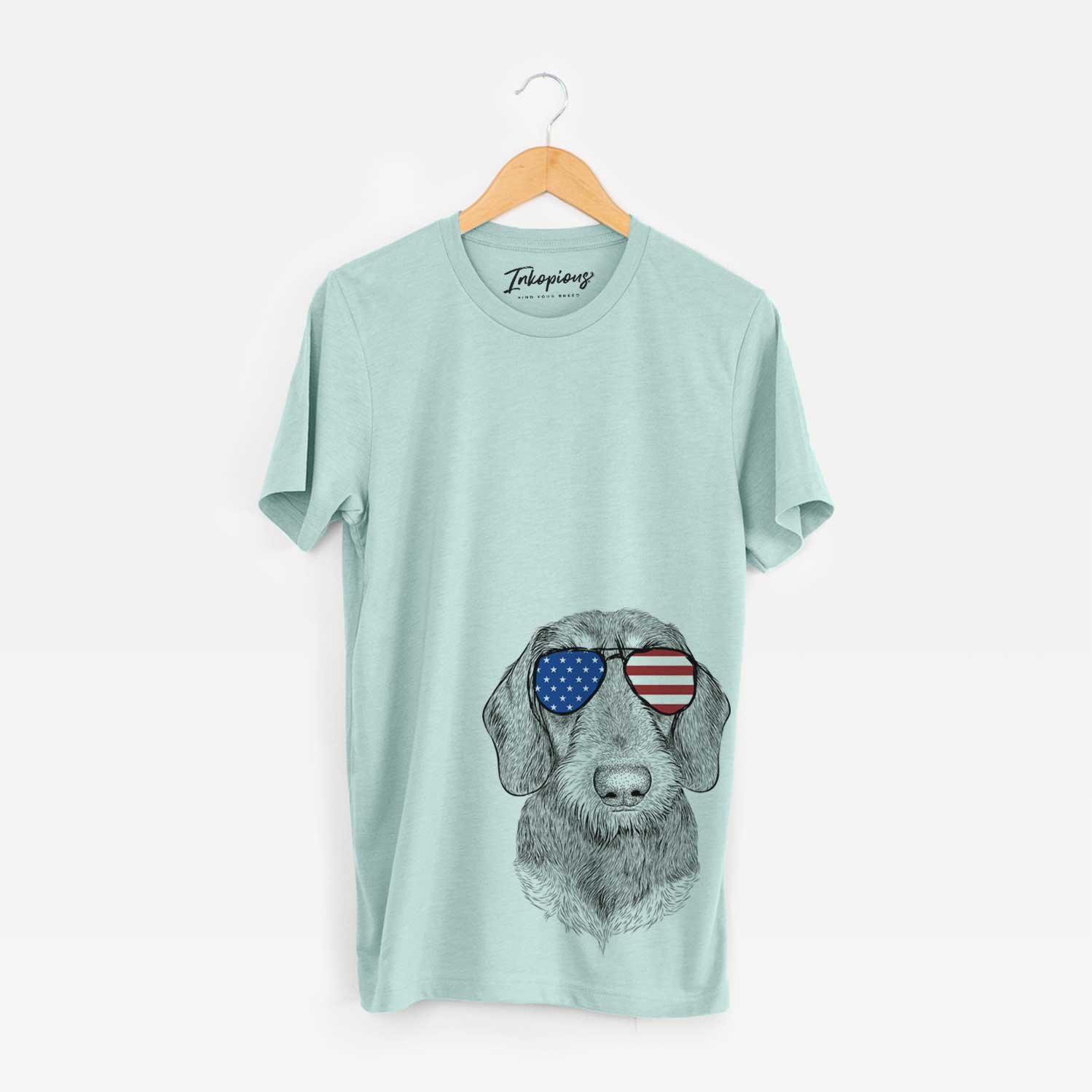 Hand-drawn sketch of Truman the Wirehaired Dachshund wearing American flag sunglasses on a Heather Sage Unisex crewneck