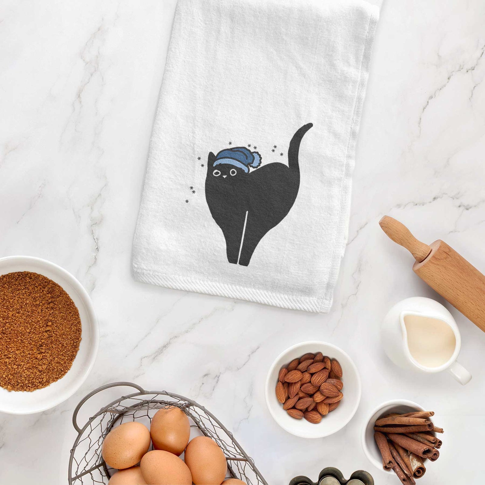 Minimalist line drawing of Bella the Black Cat wearing a winter beanie on a decorative hand towel