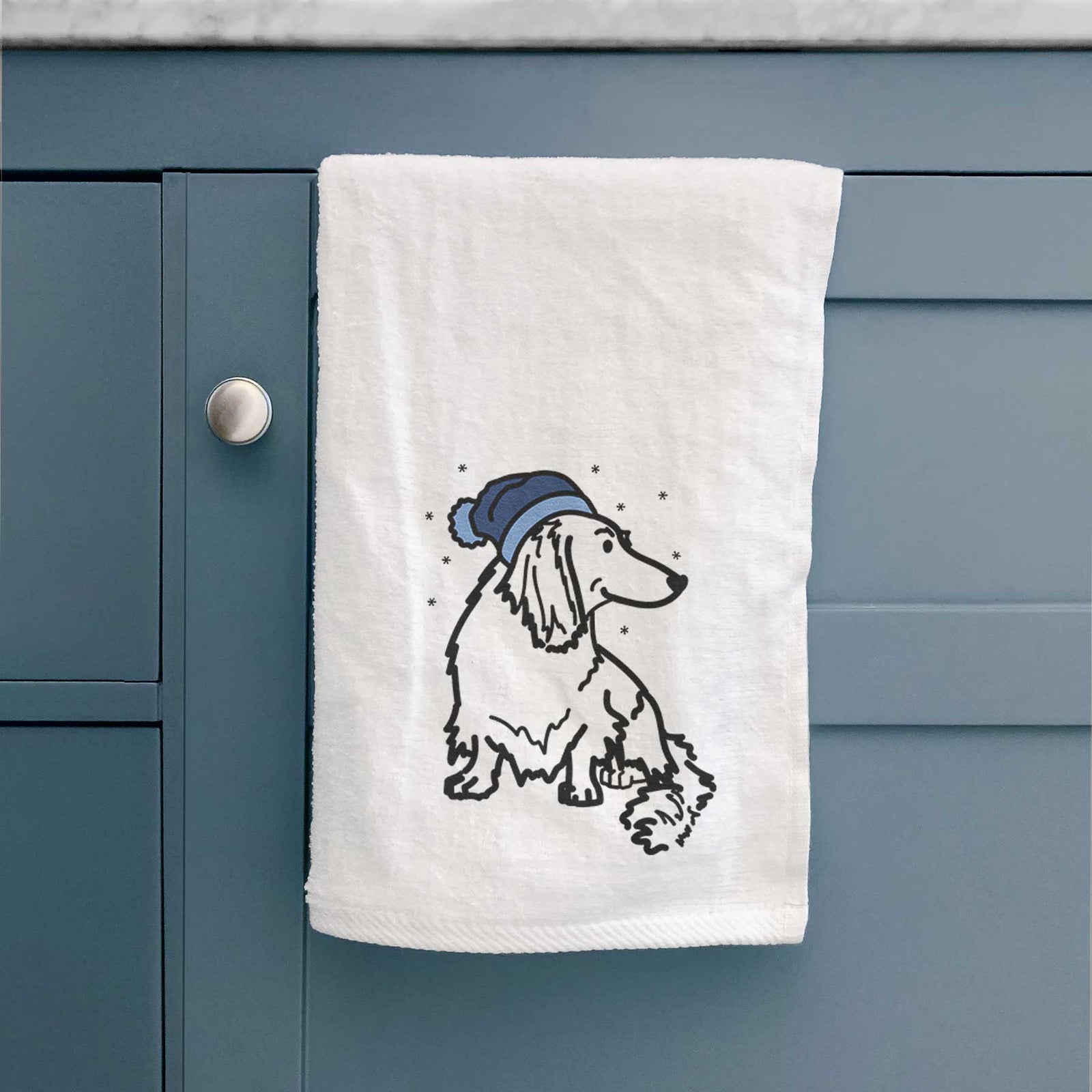 Minimalist line drawing of Bella the Dachshund wearing a winter beanie on a decorative hand towel