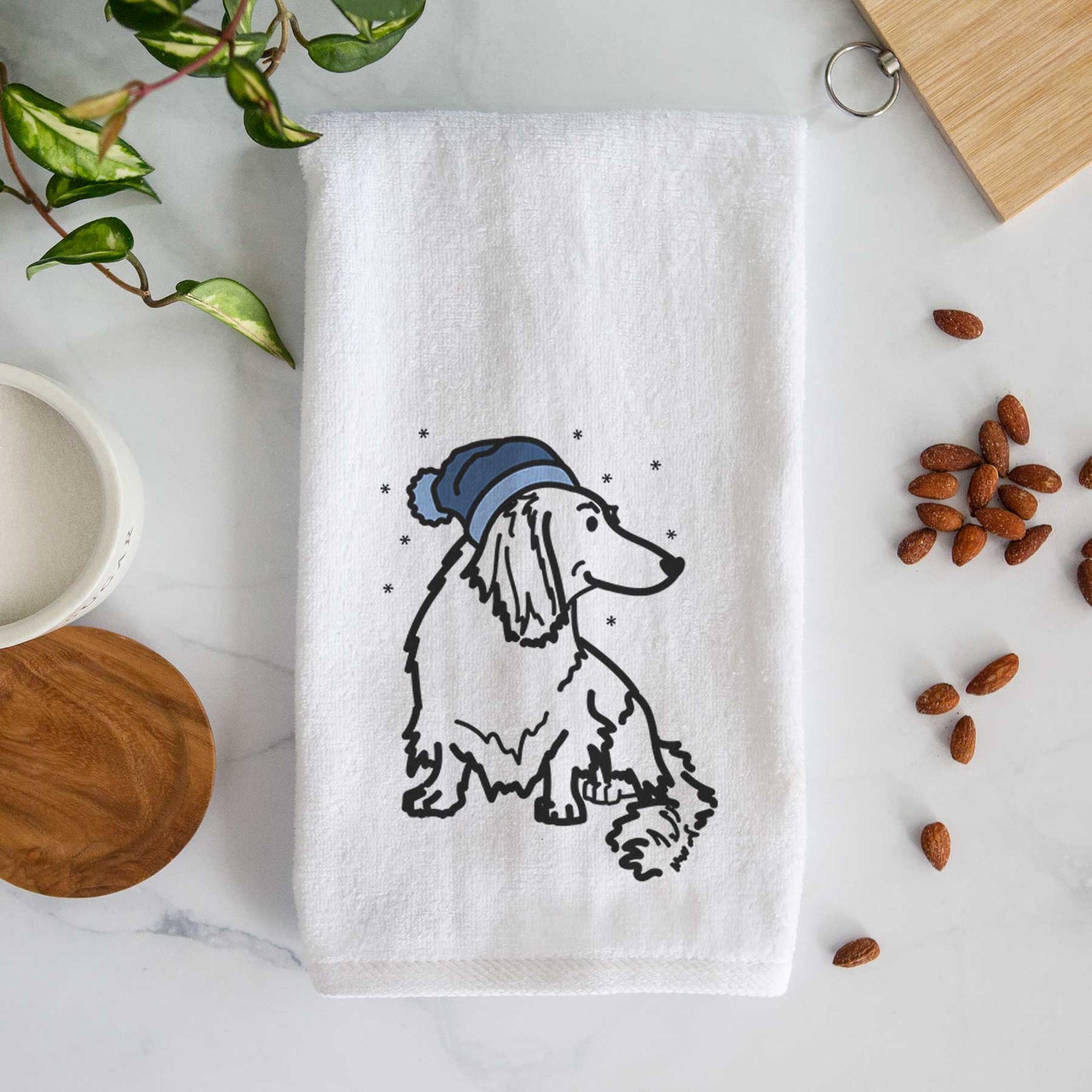 Minimalist line drawing of Bella the Dachshund wearing a winter beanie on a decorative hand towel