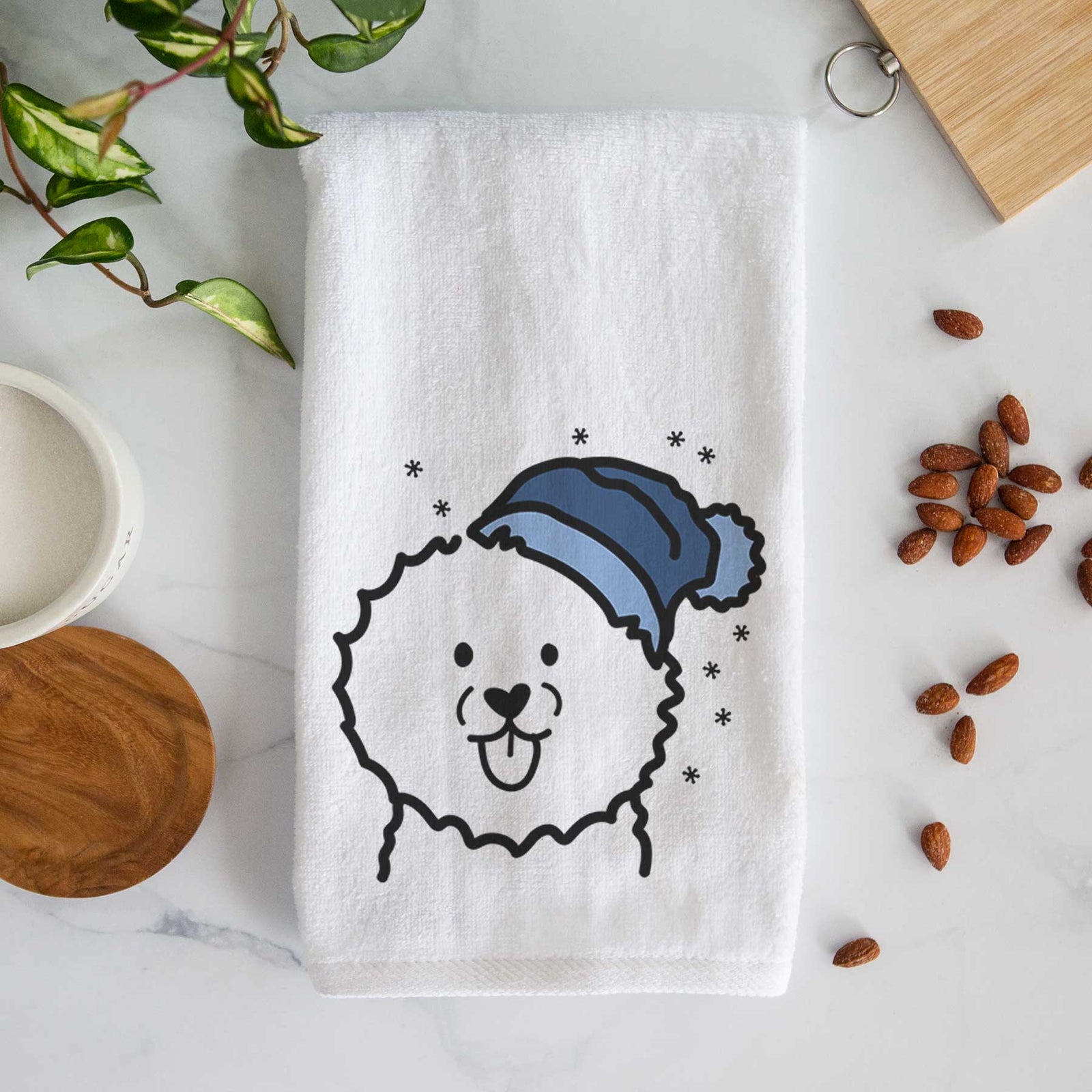 Minimalist line drawing of a Bichon Frise wearing a winter beanie on a decorative hand towel