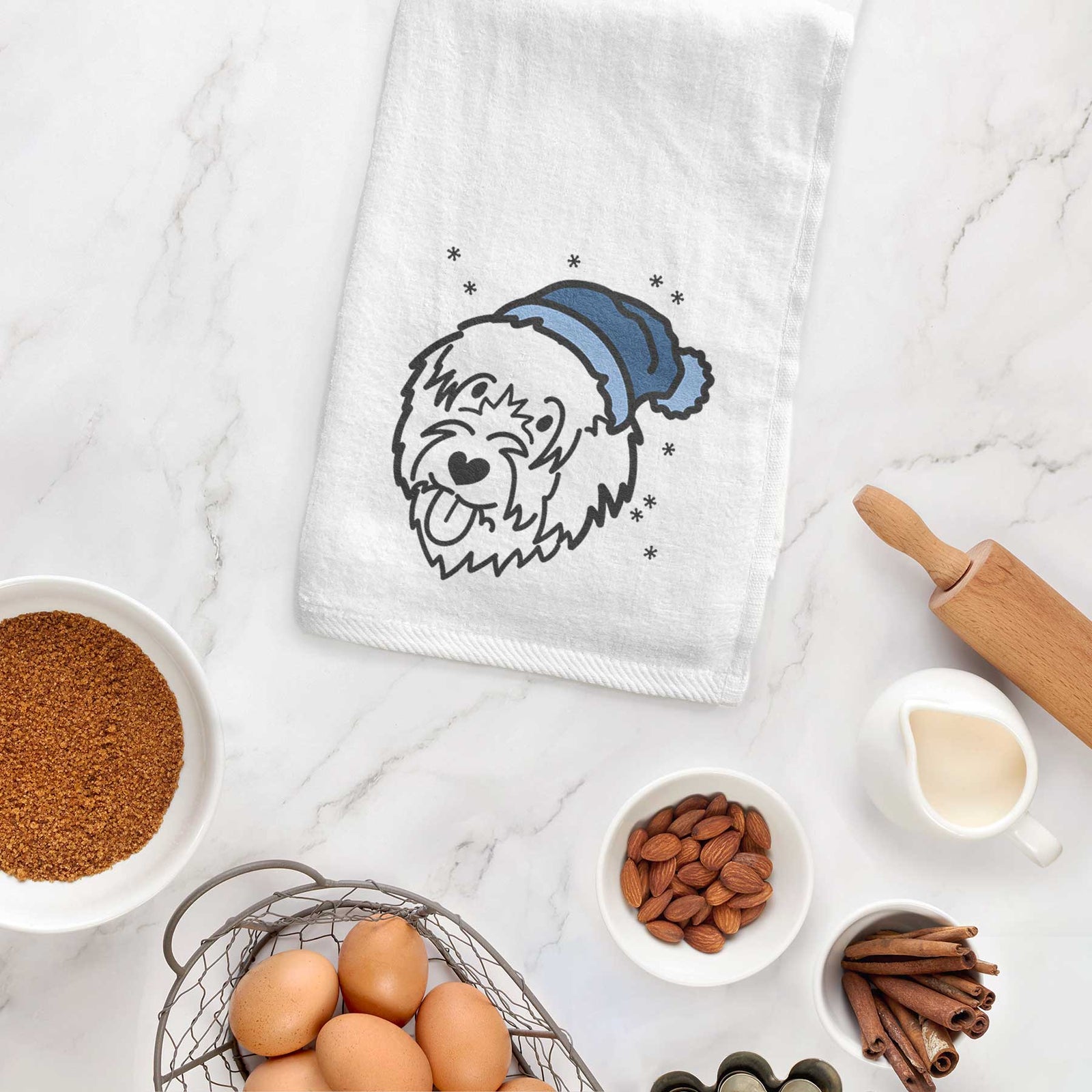 Minimalist line drawing of a Catalan Sheepdog wearing a winter beanie on a decorative hand towel