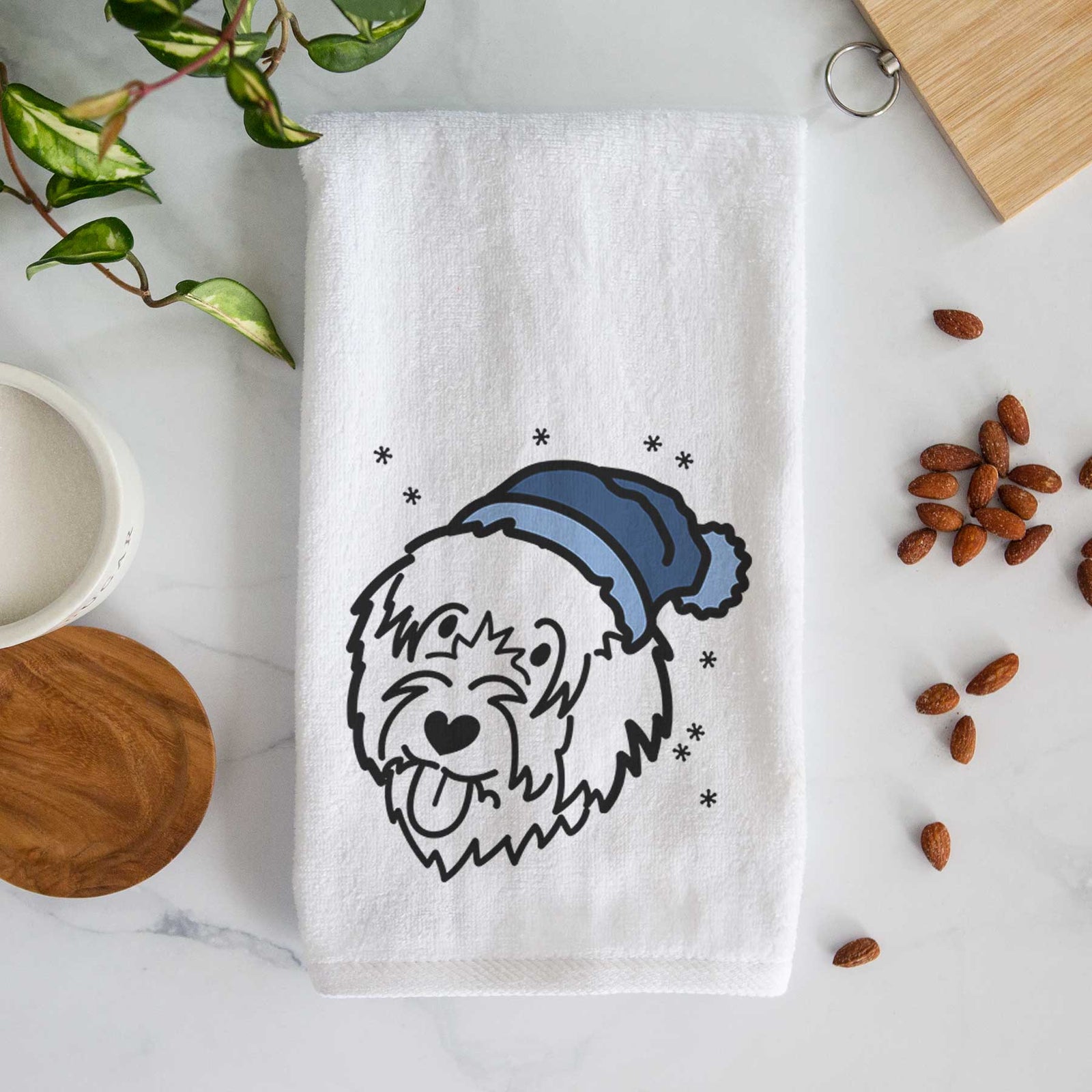 Minimalist line drawing of a Catalan Sheepdog wearing a winter beanie on a decorative hand towel
