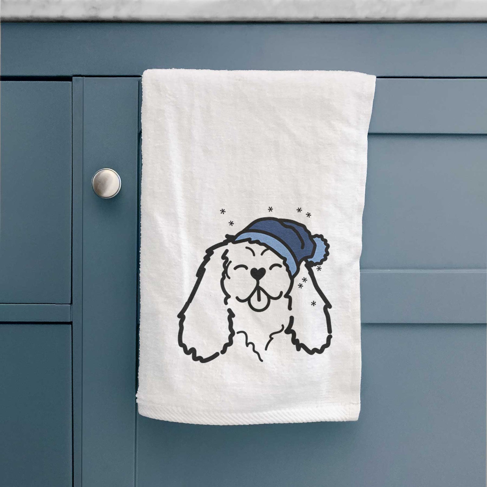 Minimalist line drawing of a Cavalier King Charles Spaniel wearing a winter beanie on a decorative hand towel