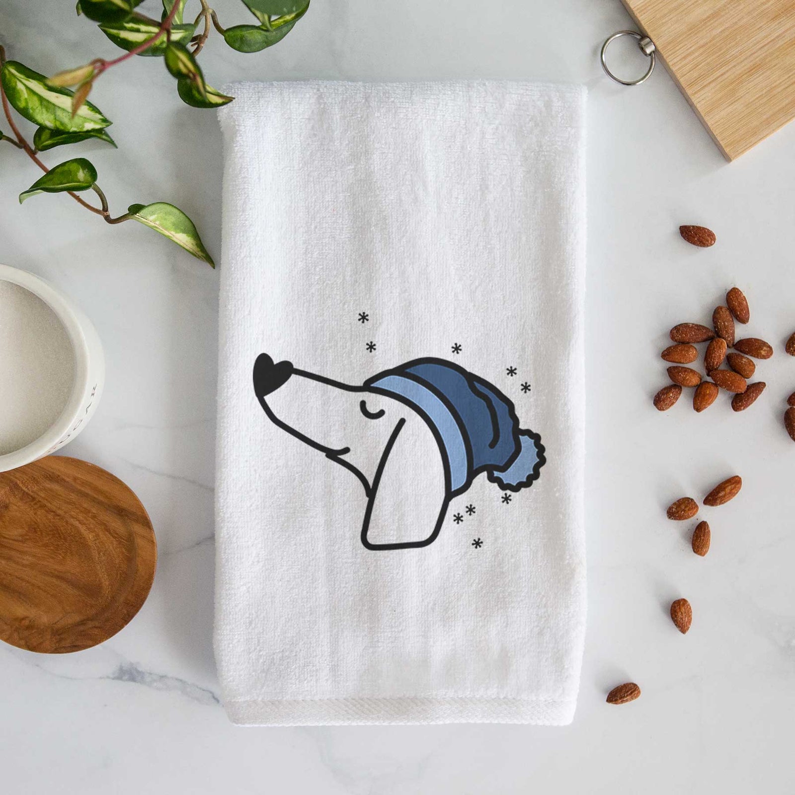 Minimalist line drawing of a Dachshund wearing a winter beanie on a decorative hand towel