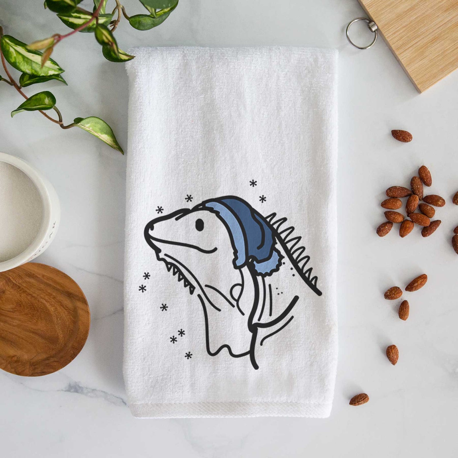 Minimalist line drawing of Louie the Iguana wearing a winter beanie on a decorative hand towel