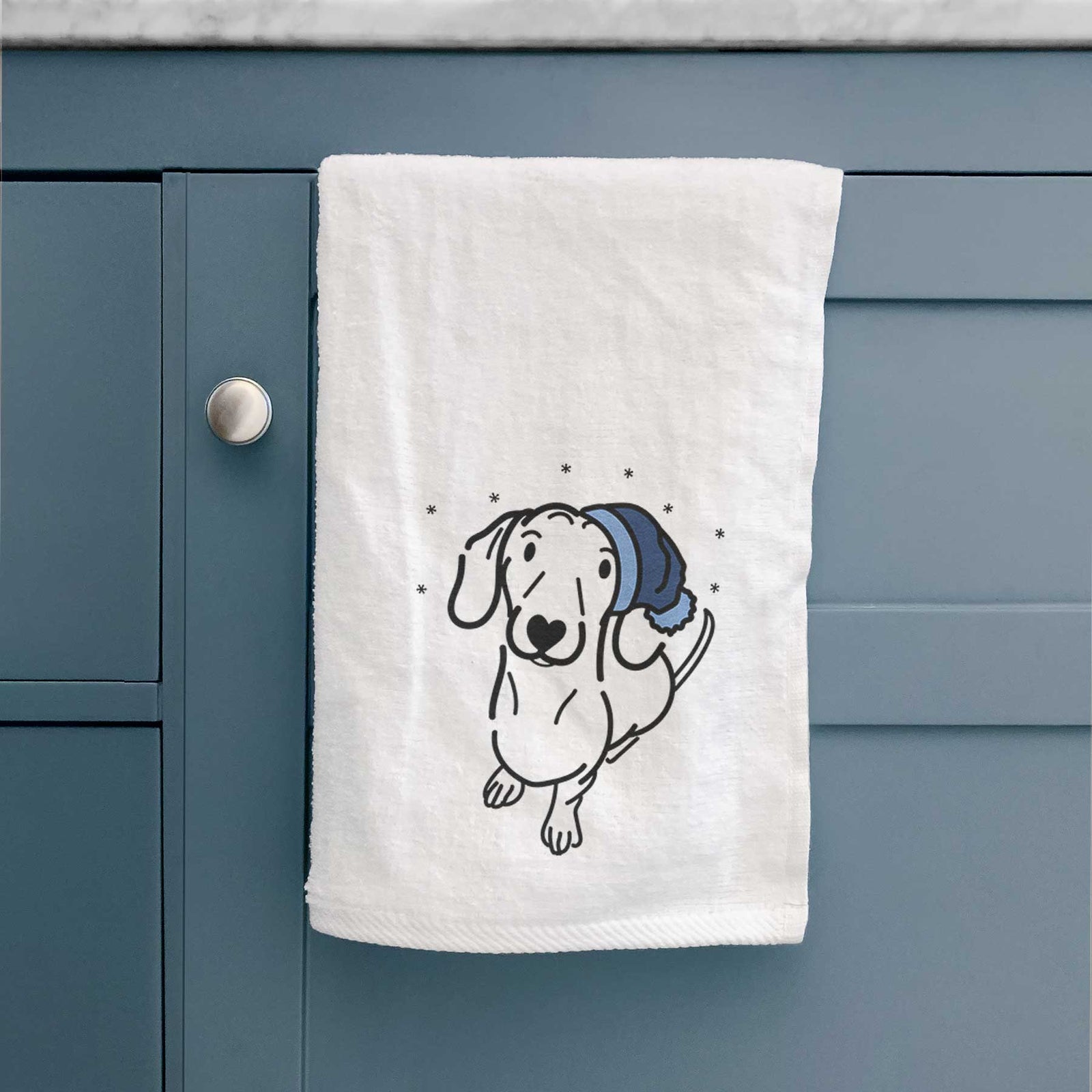 Minimalist line drawing of Moxie the Dachshund wearing a winter beanie on a decorative hand towel