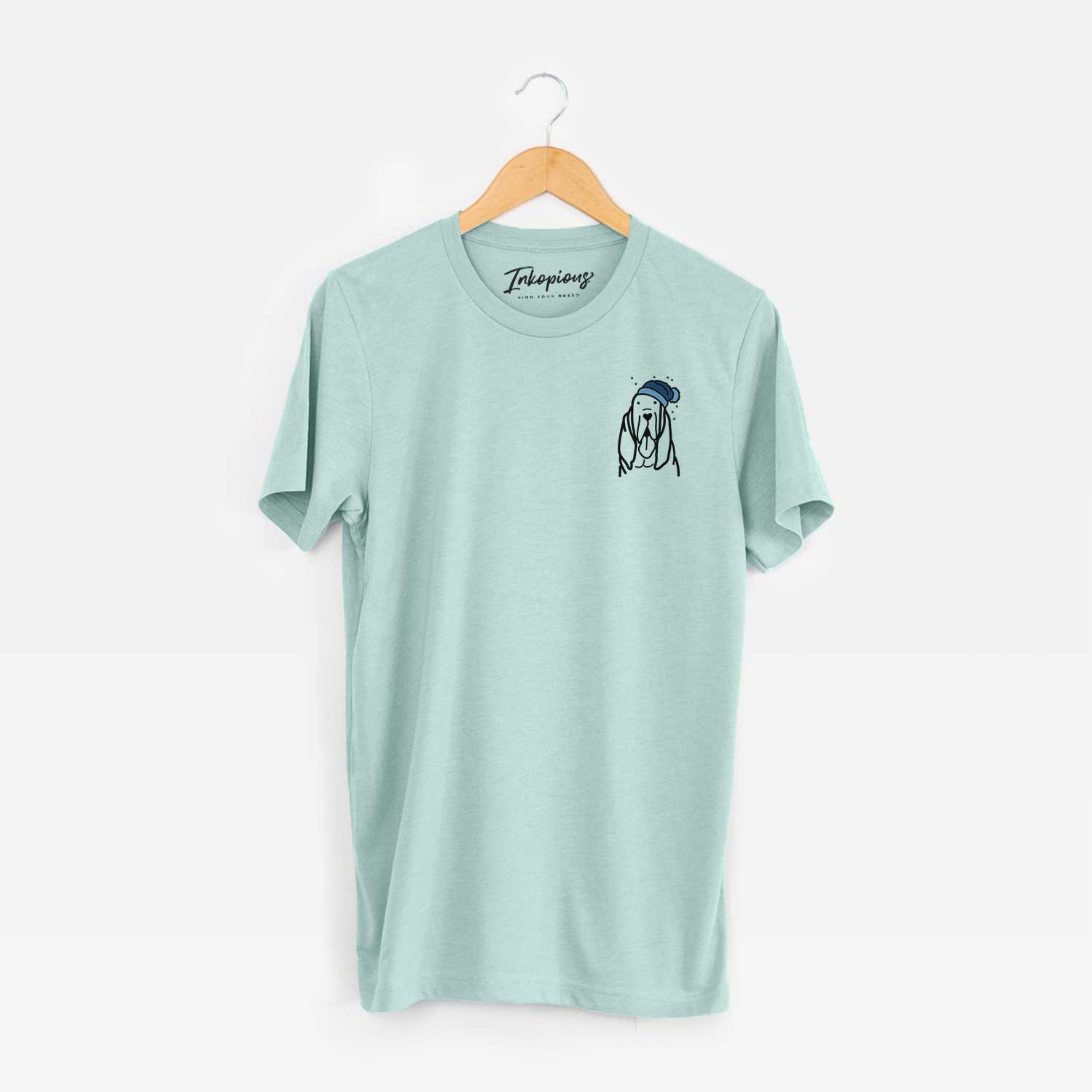 Small chest-pocket minimalist line drawing of a Bloodhound wearing a winter beanie on a Heather Sage Unisex crewneck