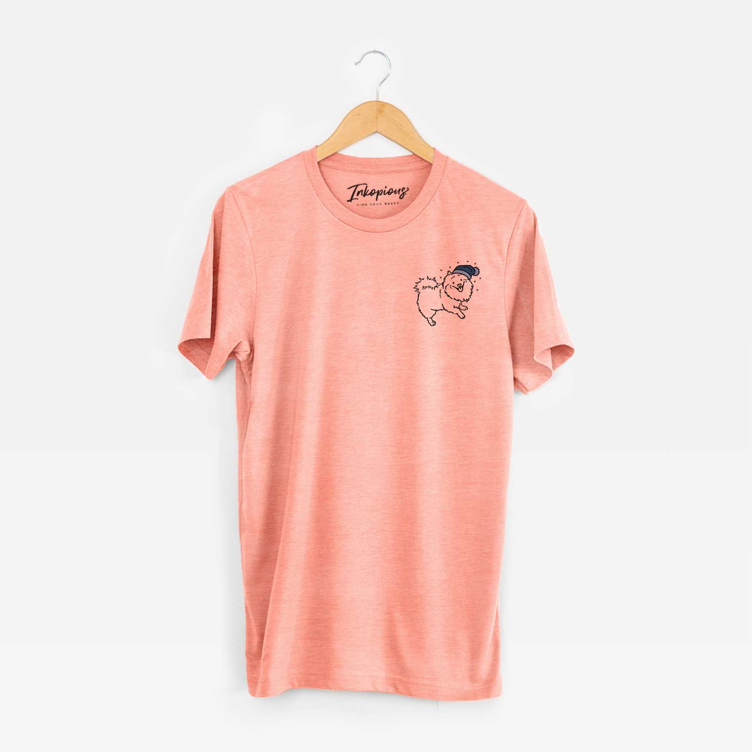 Small chest-pocket minimalist line drawing of Goldie the Pomeranian Mix wearing a winter beanie on a Sunset Unisex crewneck