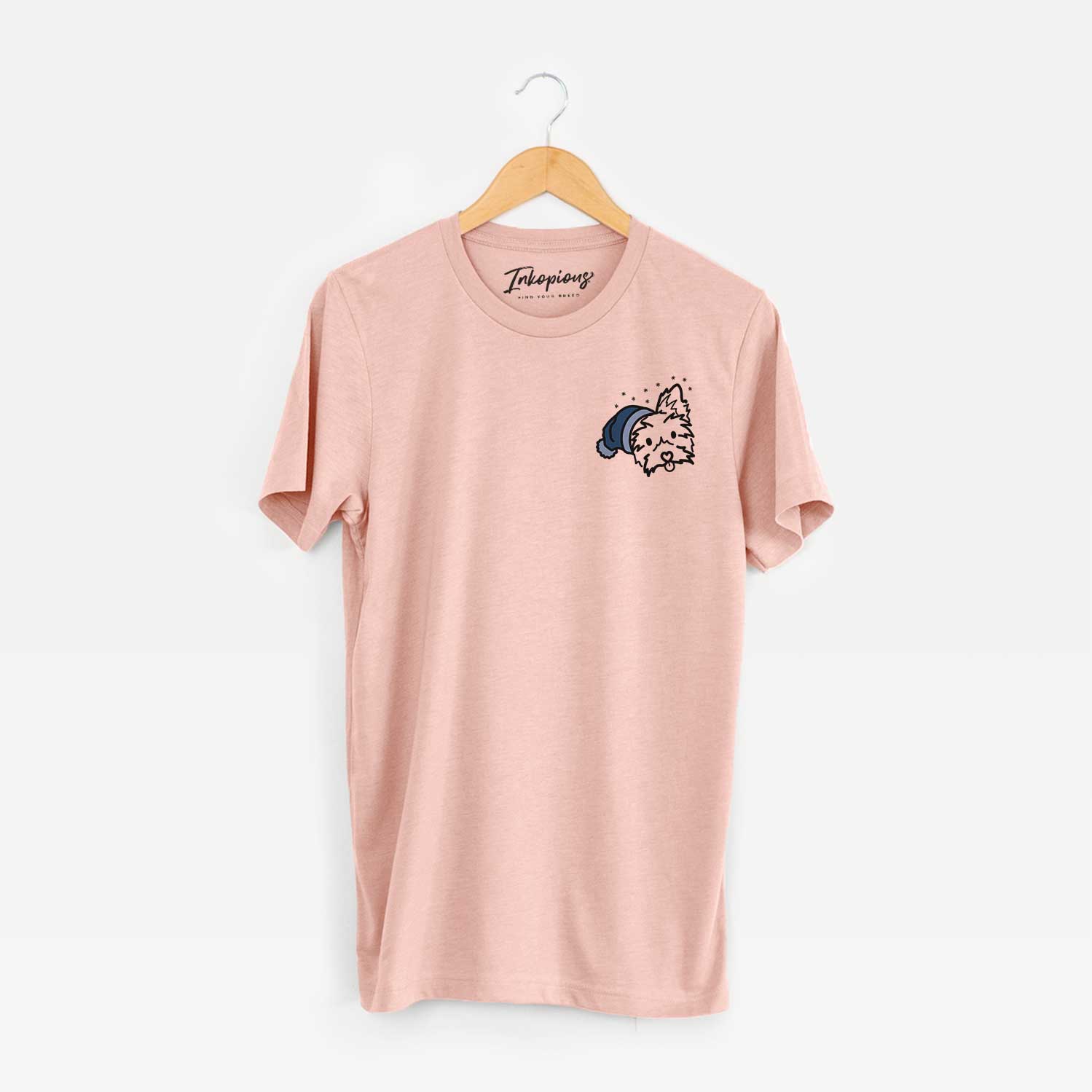 Small chest-pocket minimalist line drawing of Luna the Yorkshire Terrier wearing a winter beanie on a Peach Unisex crewneck