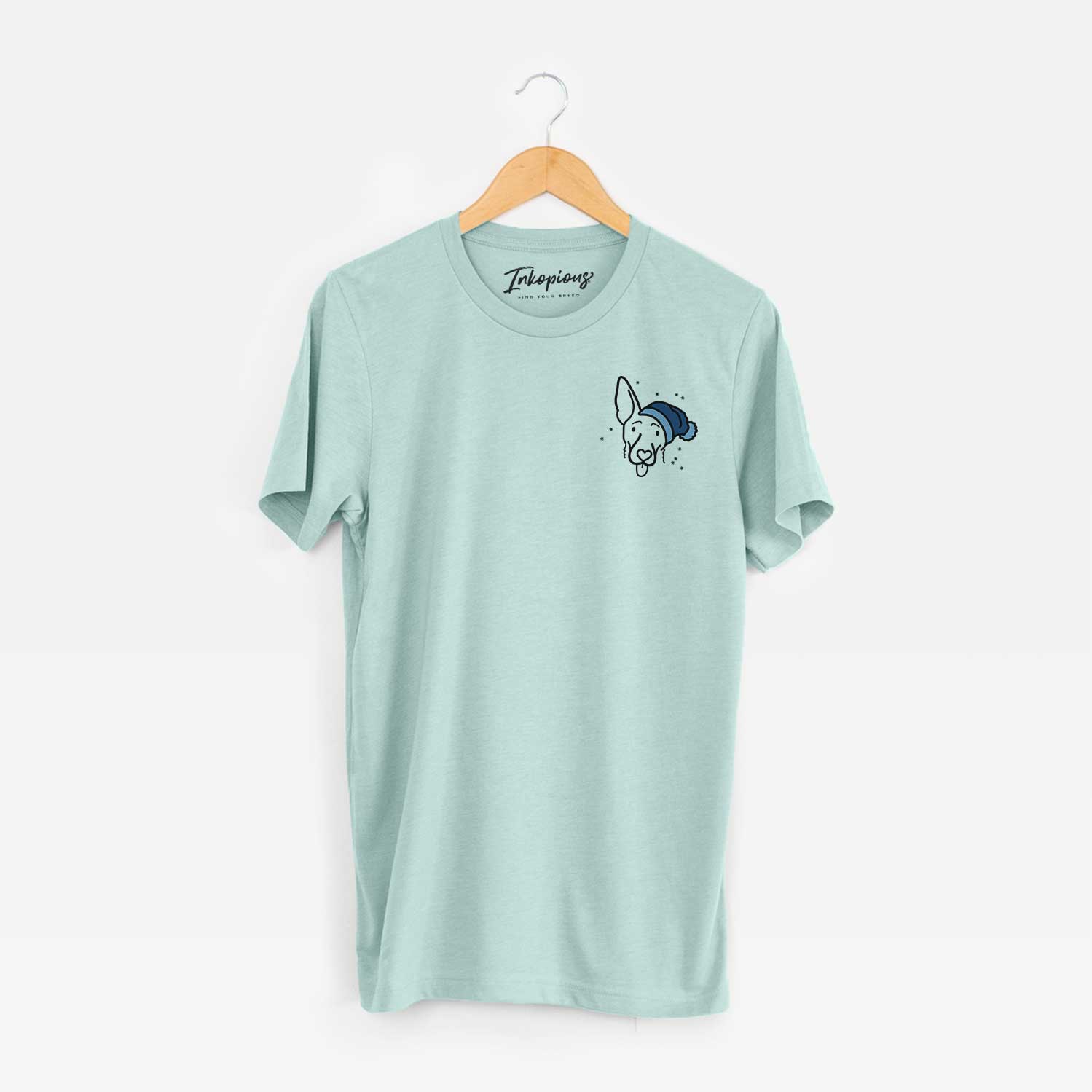 Small chest-pocket minimalist line drawing of Rosie the Shepherd Mix wearing a winter beanie on a Heather Sage Unisex crewneck