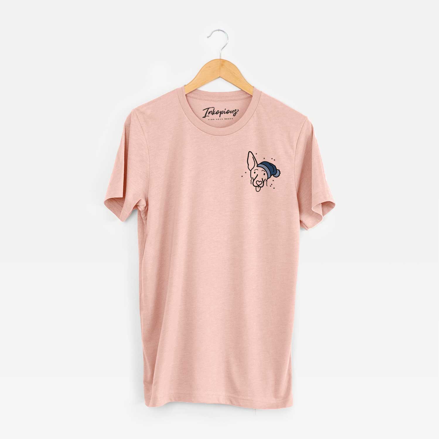Small chest-pocket minimalist line drawing of Rosie the Shepherd Mix wearing a winter beanie on a Peach Unisex crewneck