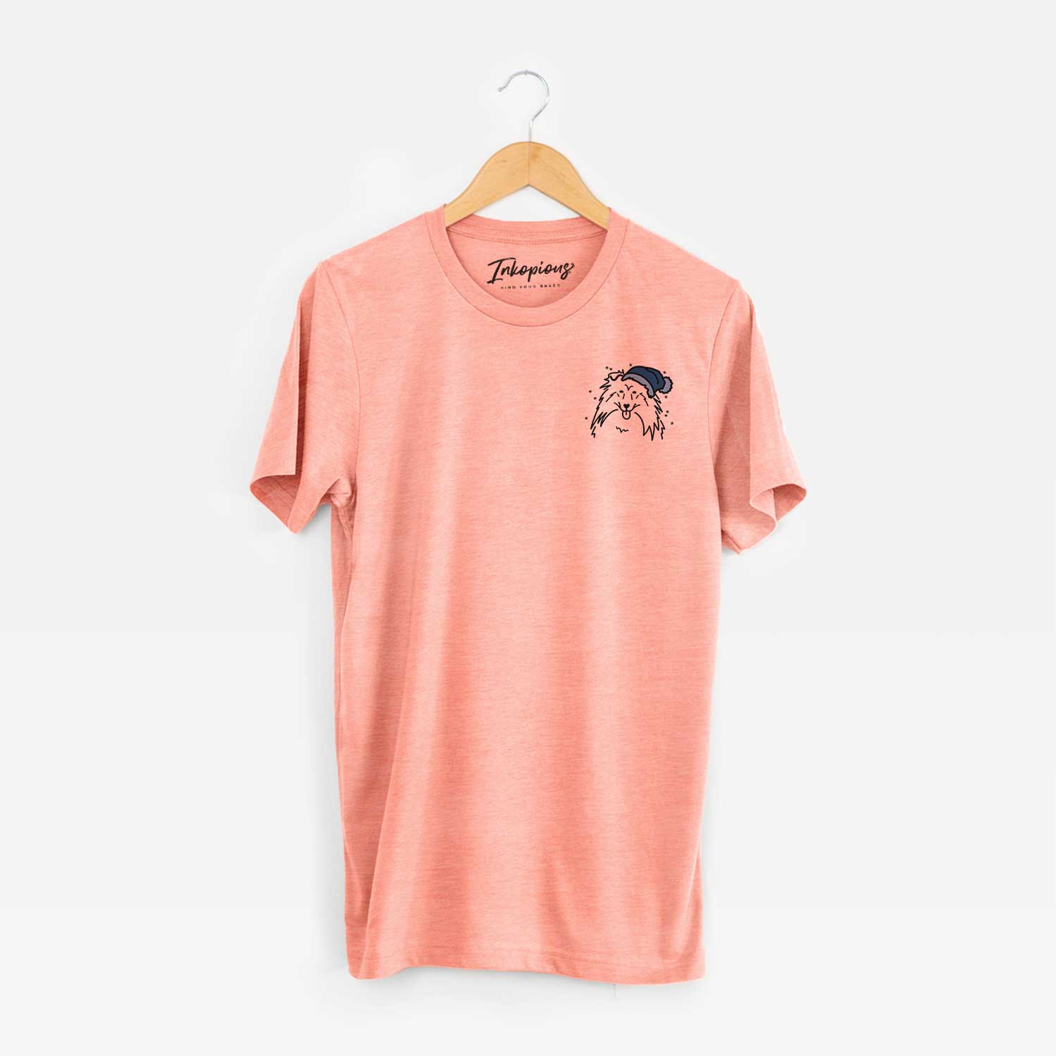 Small chest-pocket minimalist line drawing of a Rough Collie wearing a winter beanie on a Sunset Unisex crewneck