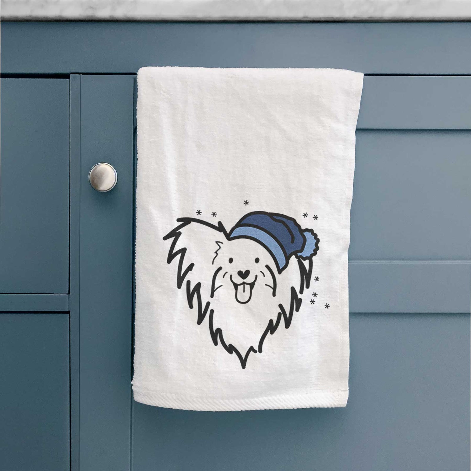 Minimalist line drawing of a Papillon wearing a winter beanie on a decorative hand towel