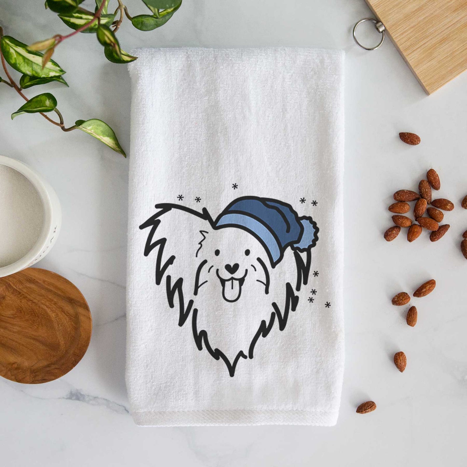 Minimalist line drawing of a Papillon wearing a winter beanie on a decorative hand towel