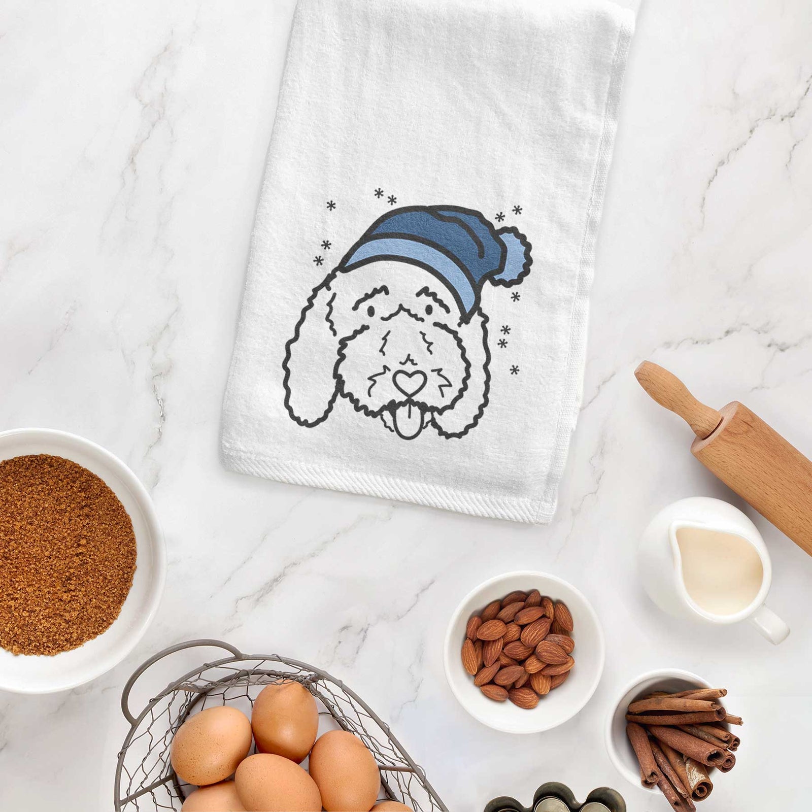 Minimalist line drawing of Ruby the Bernedoodle wearing a winter beanie on a decorative hand towel