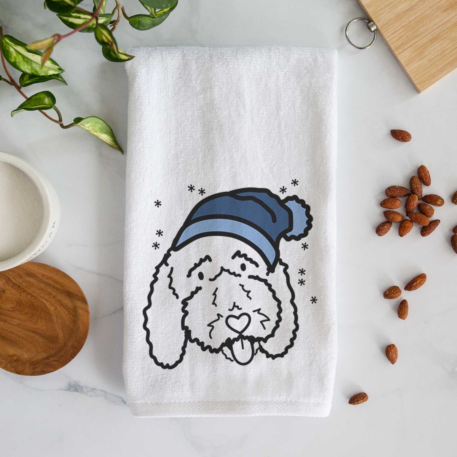Minimalist line drawing of Ruby the Bernedoodle wearing a winter beanie on a decorative hand towel