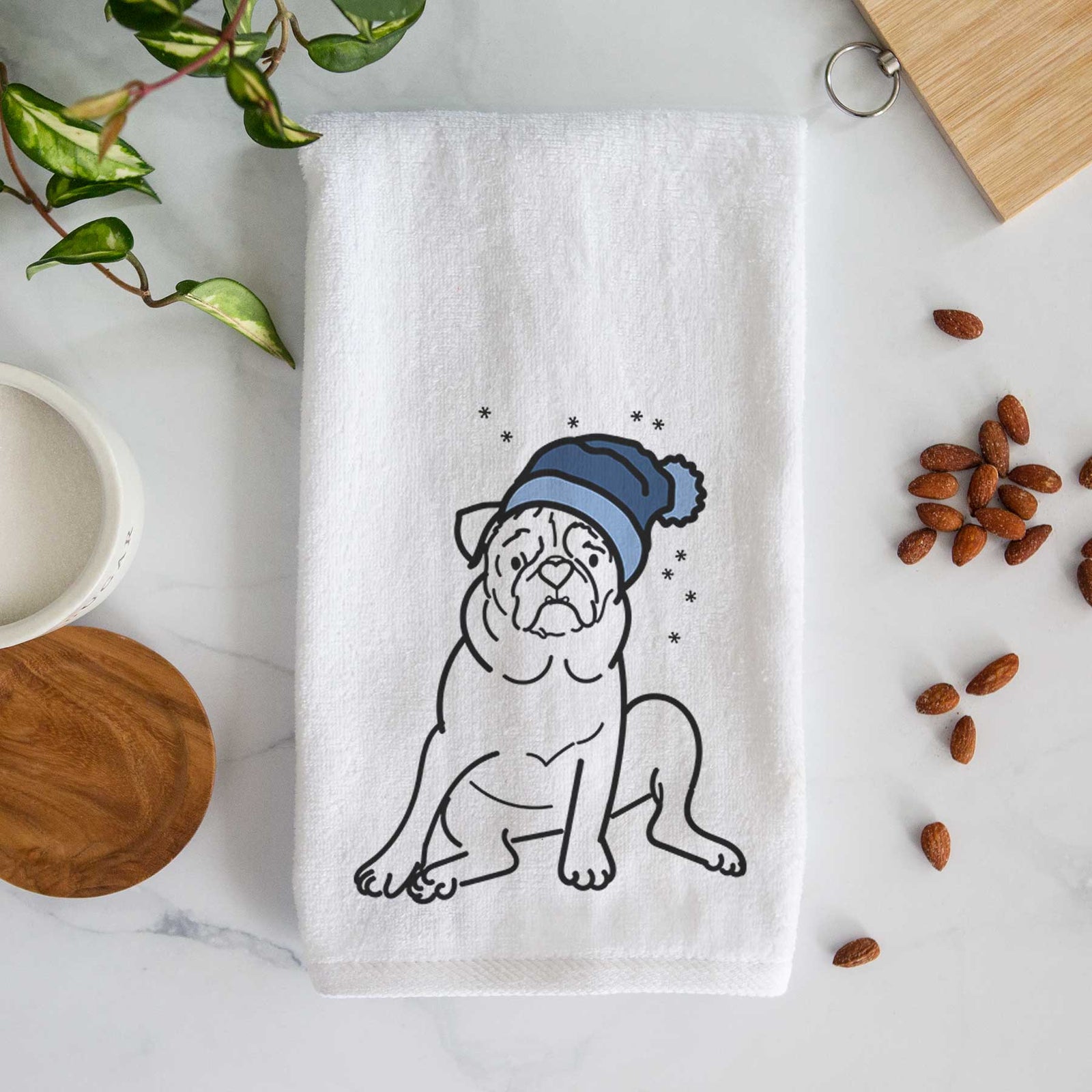 Minimalist line drawing of Rudy the Pug wearing a winter beanie on a decorative hand towel