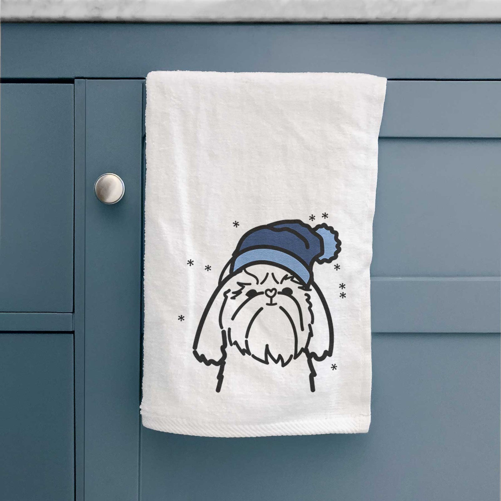 Minimalist line drawing of a Shih Tzu wearing a winter beanie on a decorative hand towel