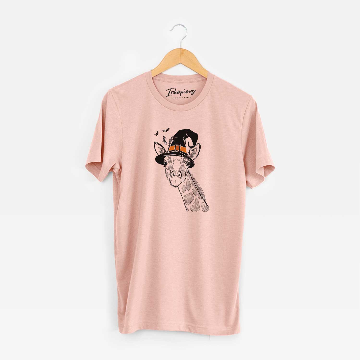 Hand-drawn sketch of Cedrick the Giraffe wearing a witch hat on a Peach Unisex crewneck