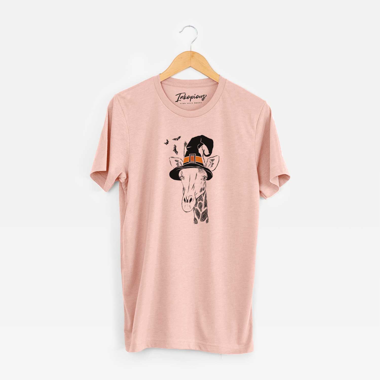 Hand-drawn sketch of Geoffrey the Giraffe wearing a witch hat on a Peach Unisex crewneck