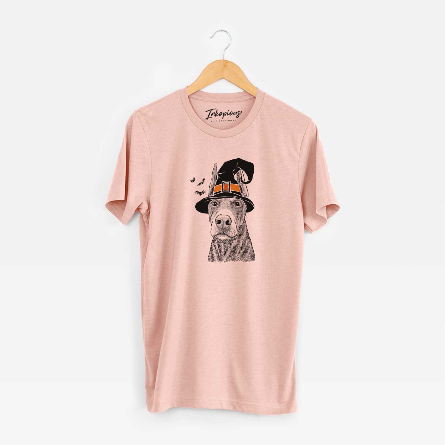 Hand-drawn sketch of Luna the Doberman Pinscher wearing a witch hat on a Peach Unisex crewneck