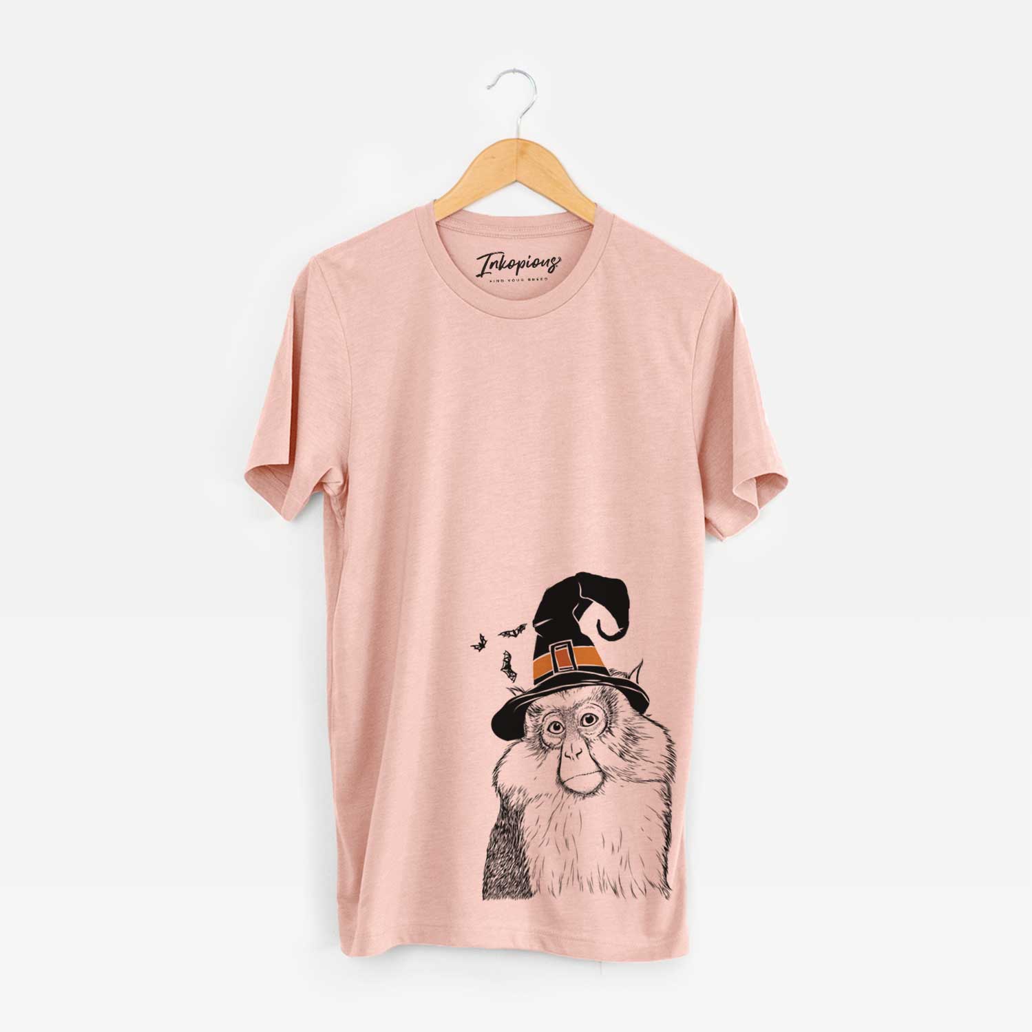 Hand-drawn sketch of Matata the Mona Monkey wearing a witch hat on a Peach Unisex crewneck