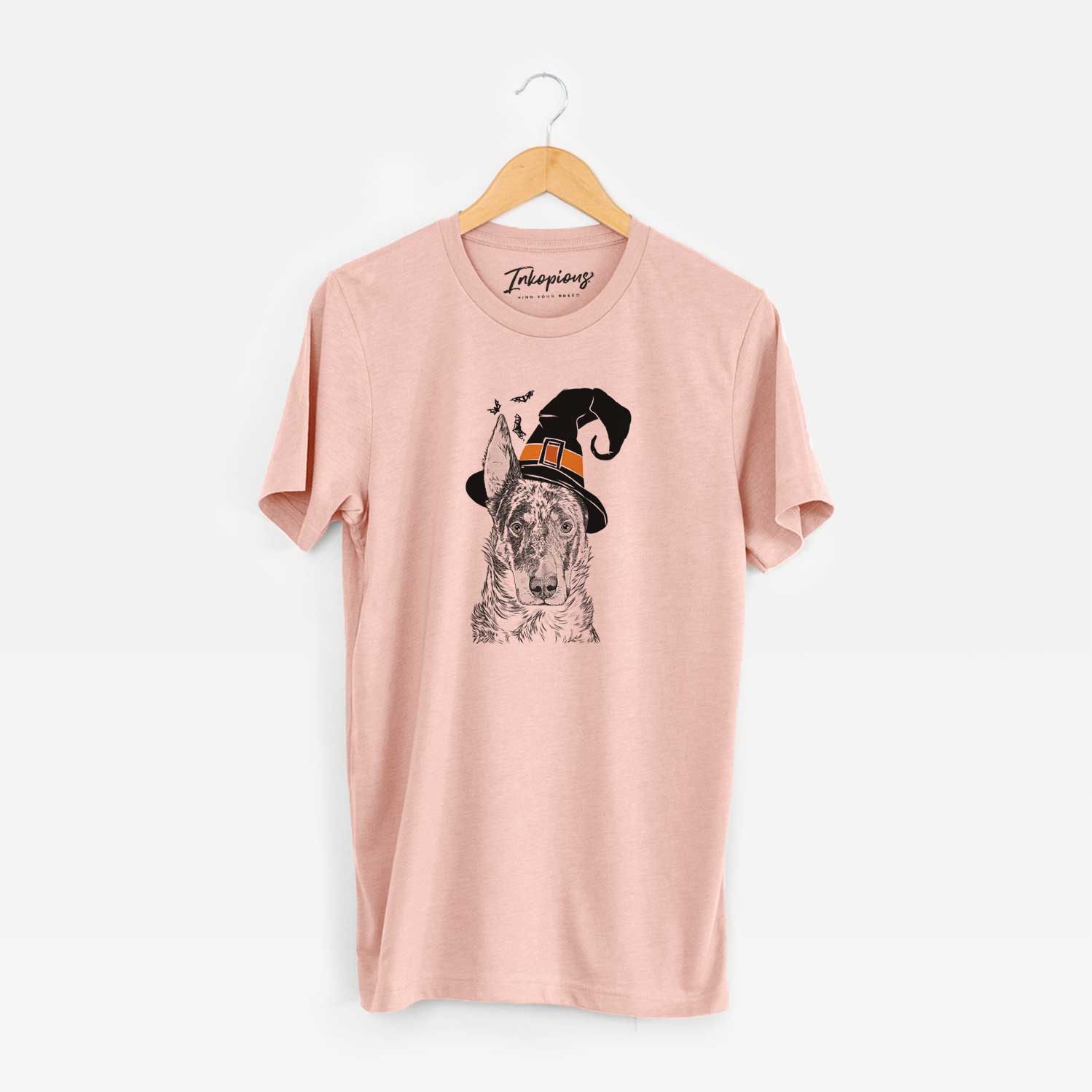Hand-drawn sketch of Nori the Beauceron wearing a witch hat on a Peach Unisex crewneck